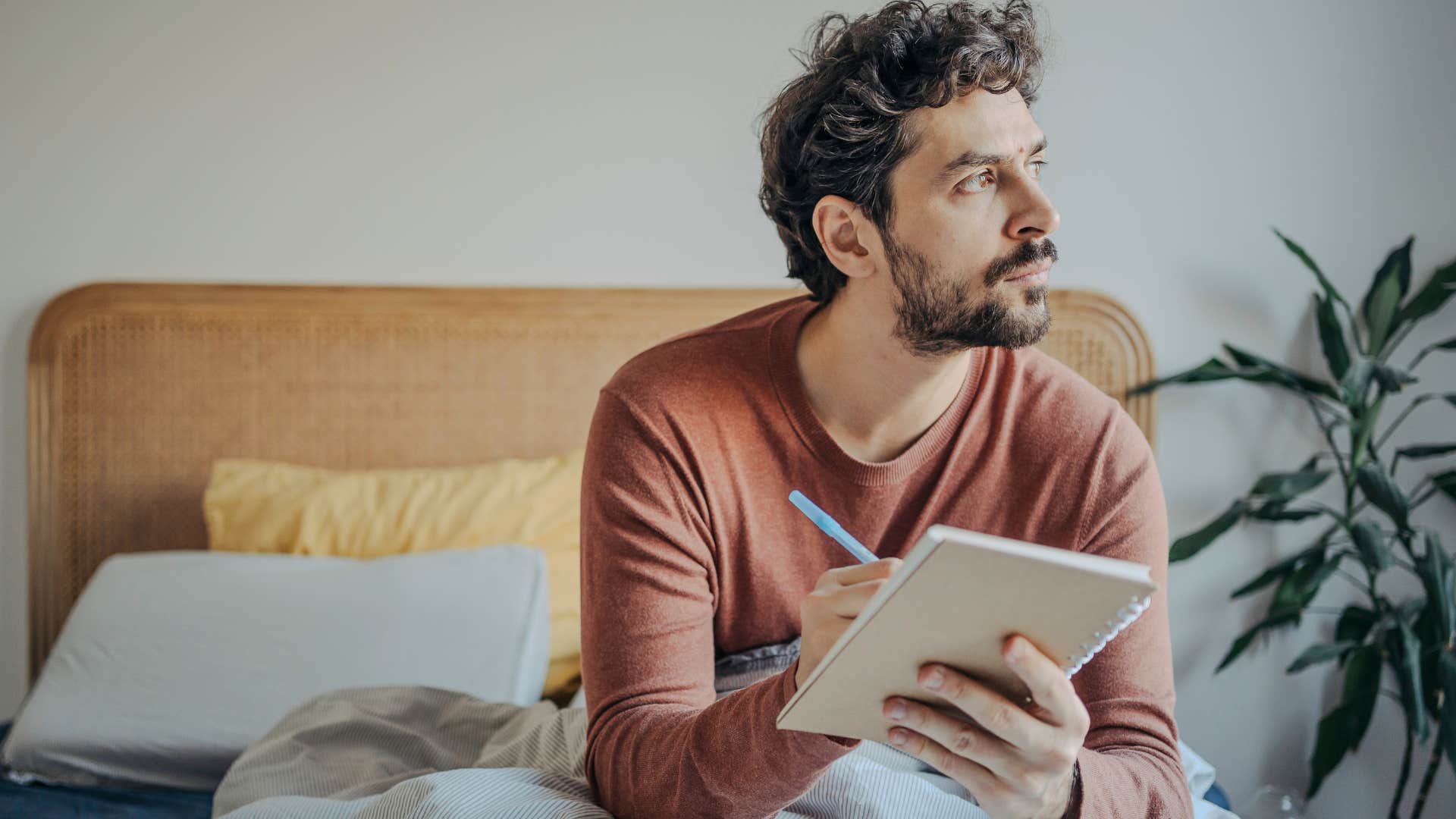 man sitting up in bed journaling
