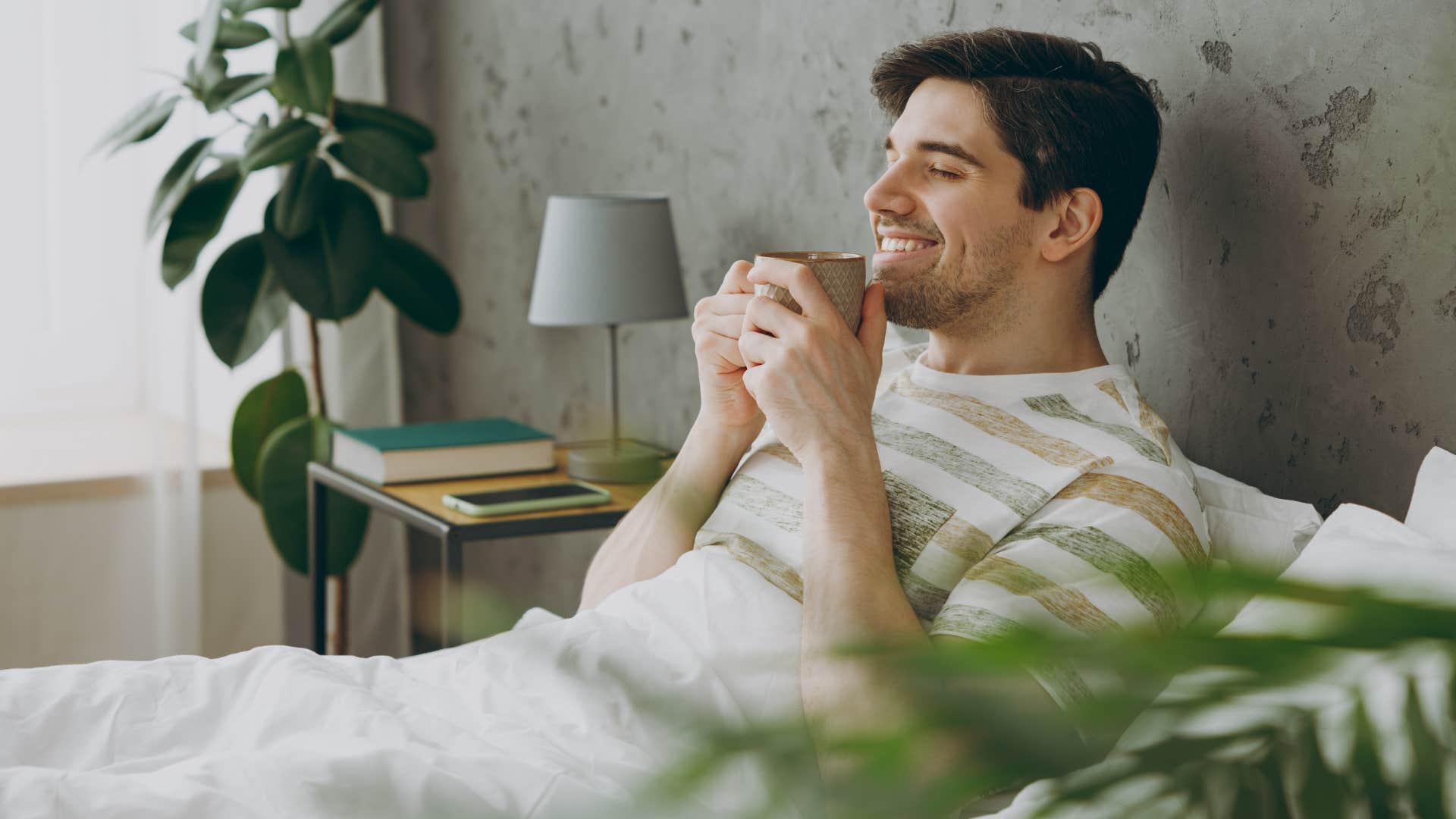 man enjoying his nighttime comfort drink laying in bed