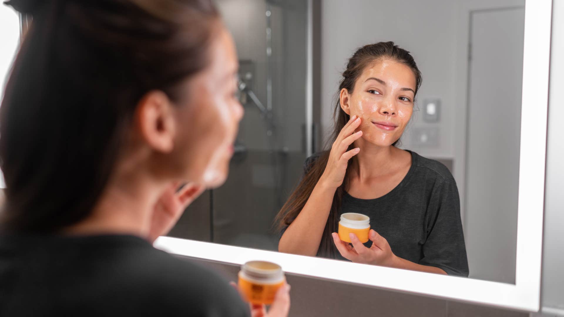 woman putting on her skincare products after showering