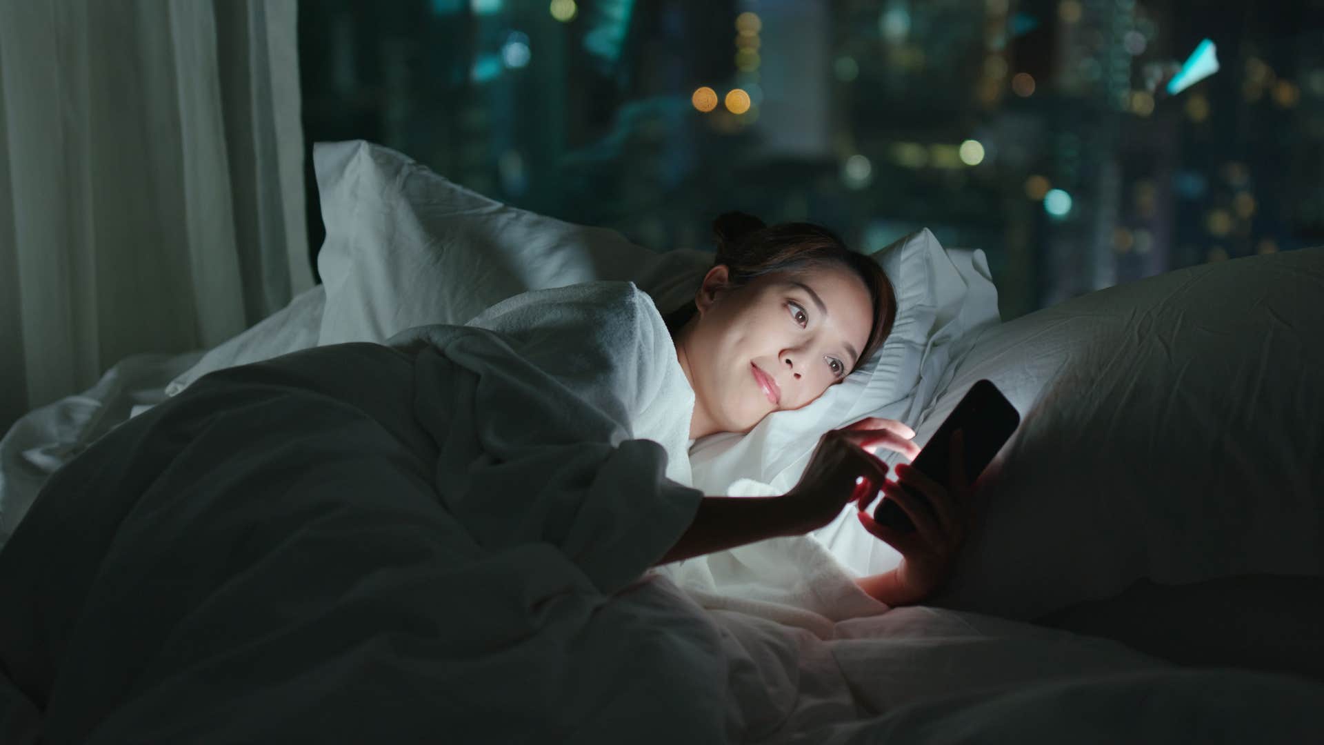 woman using her phone as a sound machine in bed