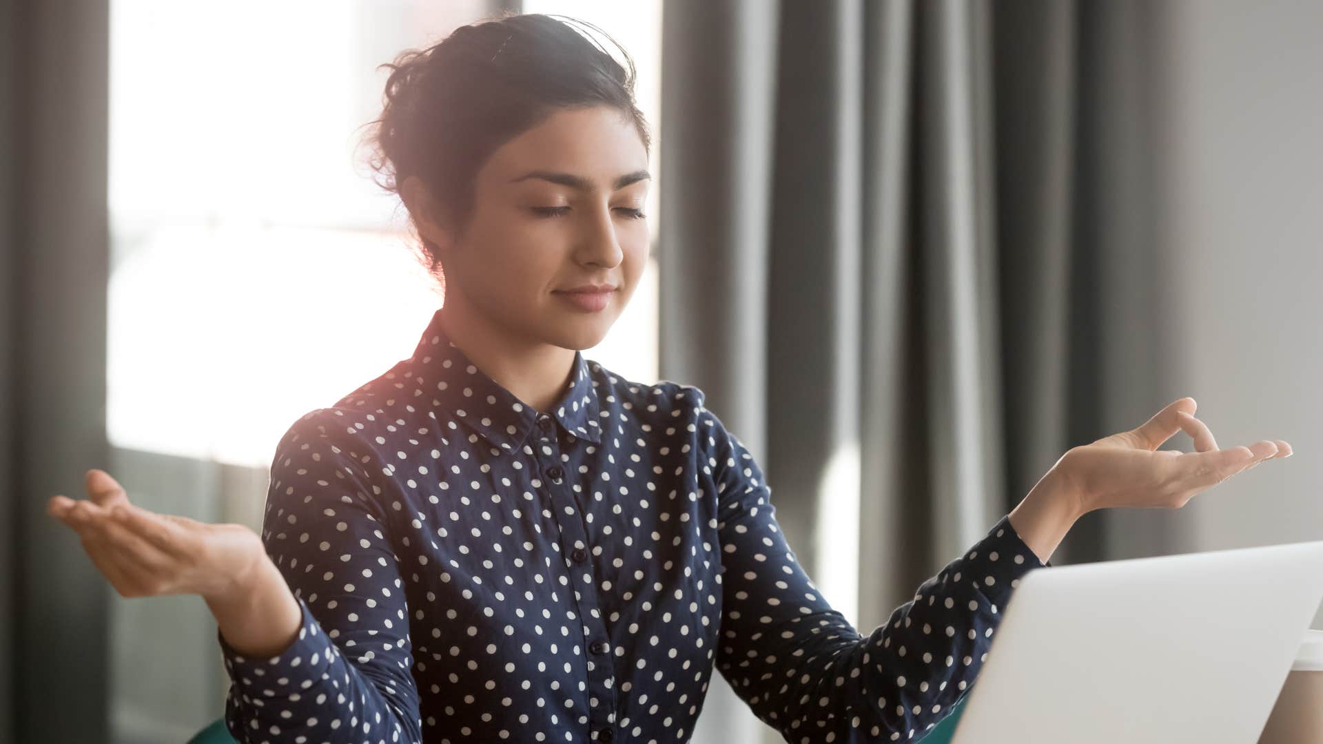 a woman keeps calm under pressure while doing work on her laptop