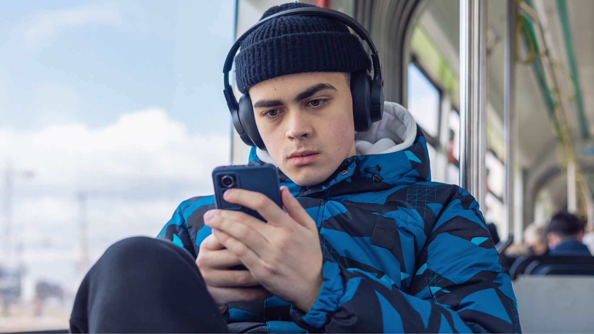 Gen Z man taking public transportation looking at his phone