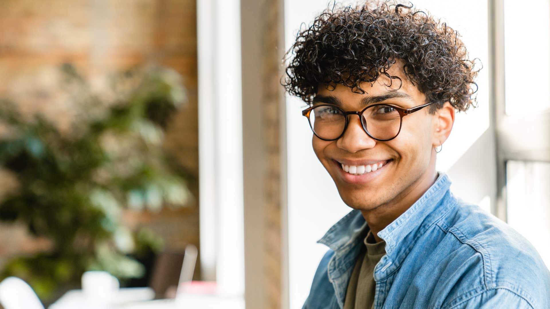 Gen Z man smiling while doing a side hustle for work
