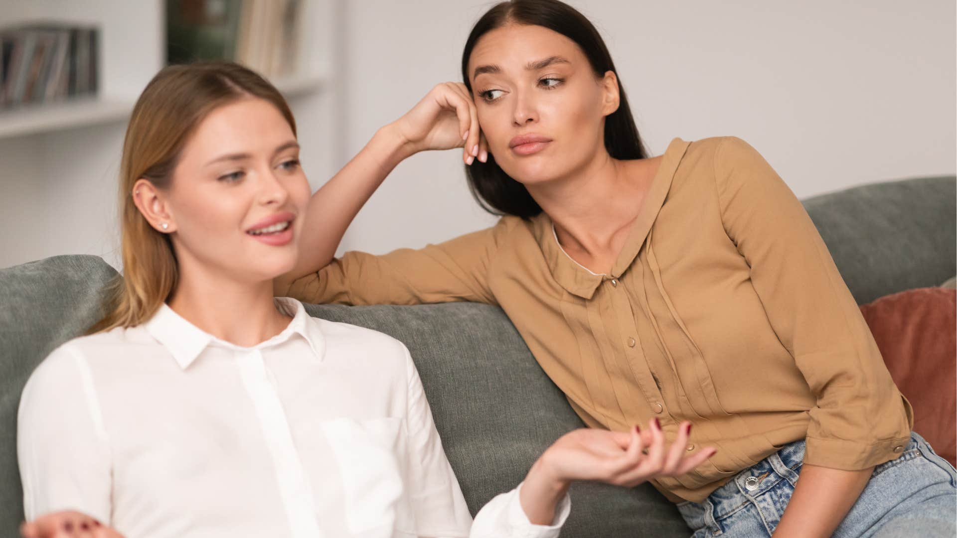 Woman being a one-upper and looking annoyed next to her friend.