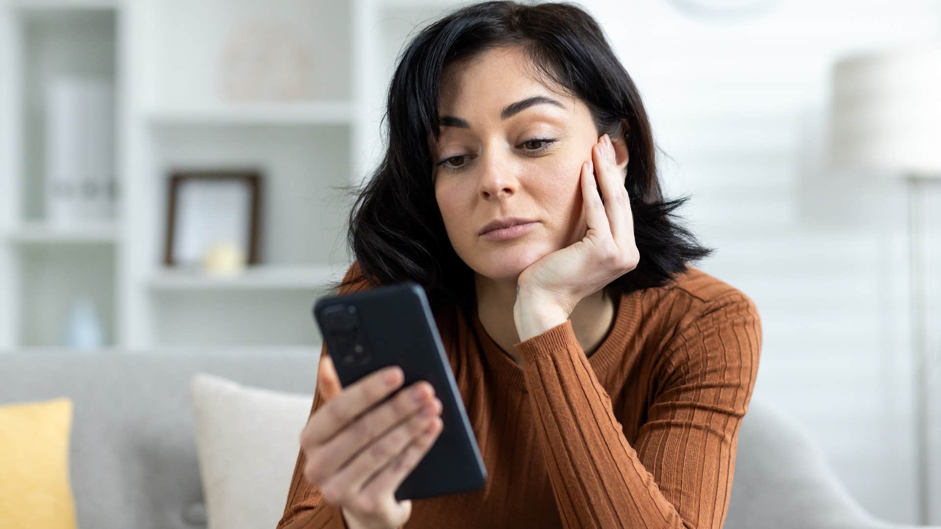 Woman constantly checking her phone at home.