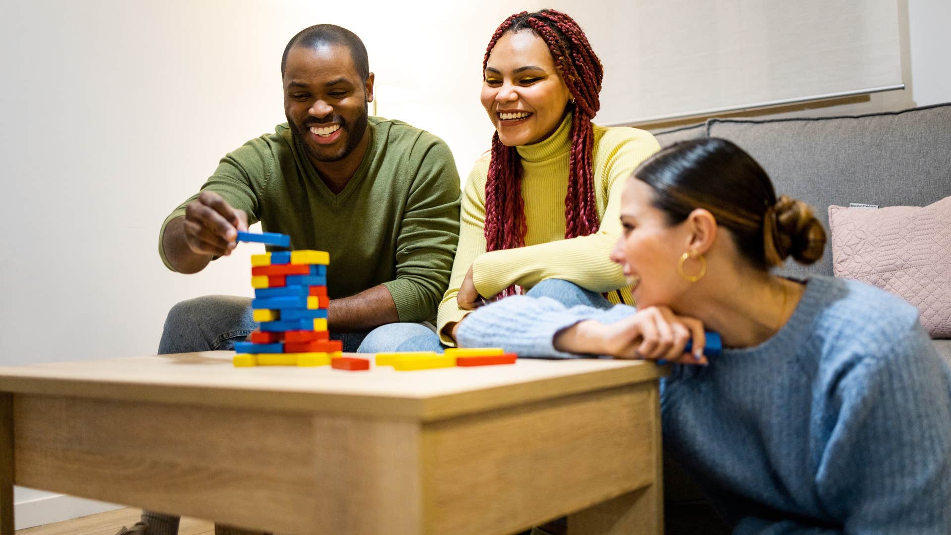 group of friends hosting game night as they play jenga game