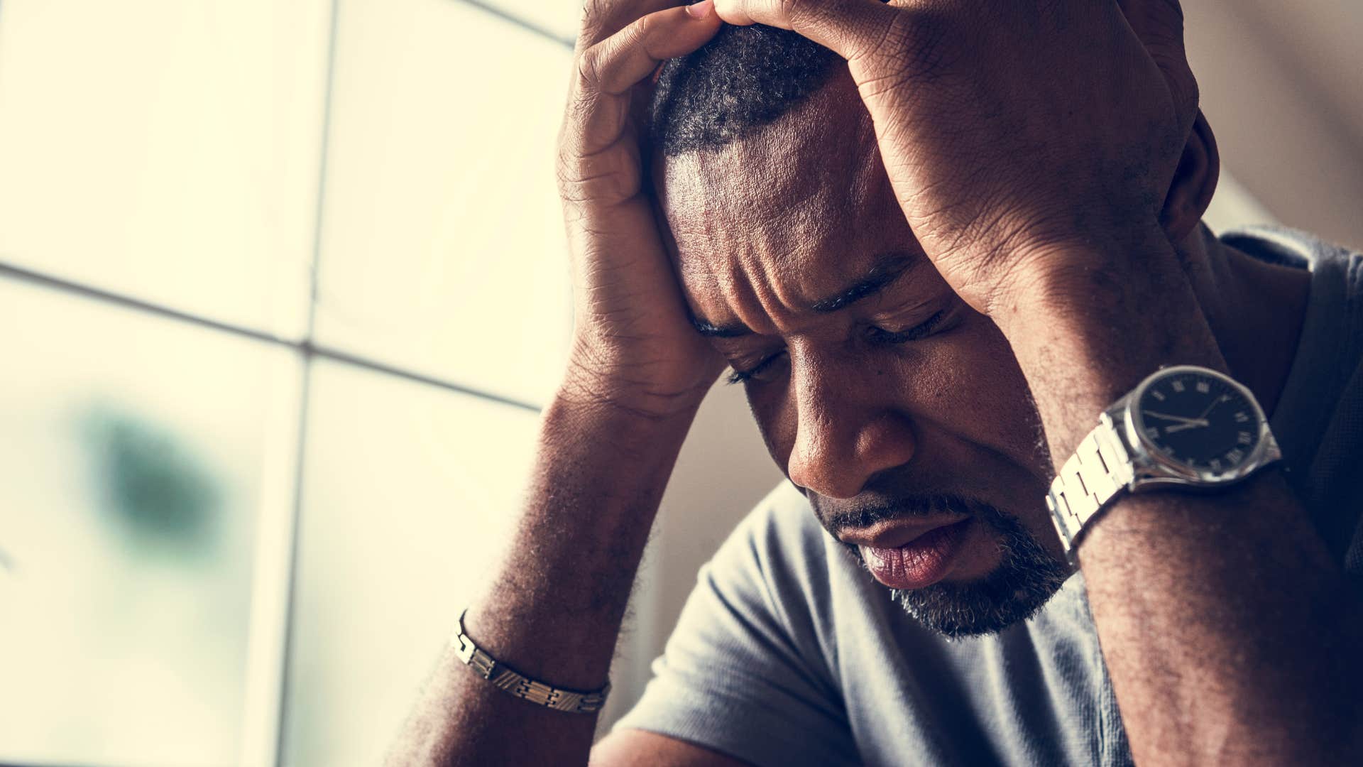 burnt out man holding his head in his hands