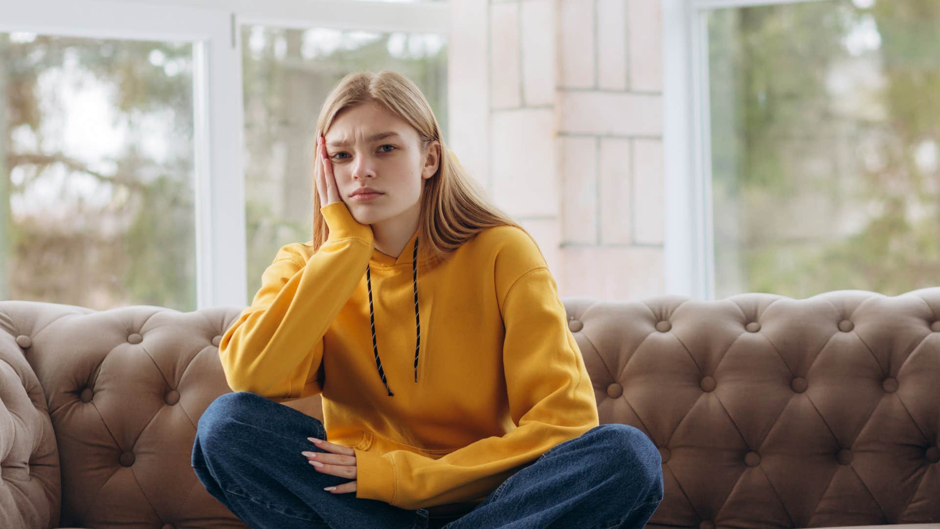 a woman sits on her couch wondering why her boyfriend ghosted her after an argument