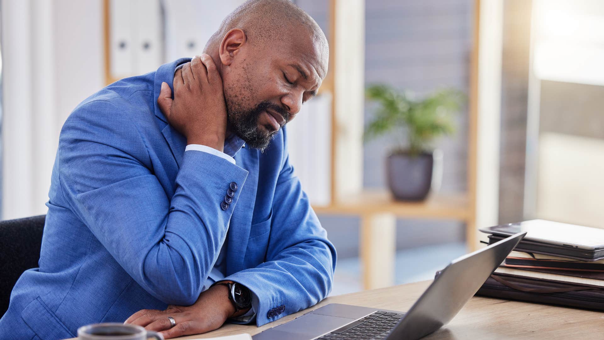burnt out man holding his neck at his desk