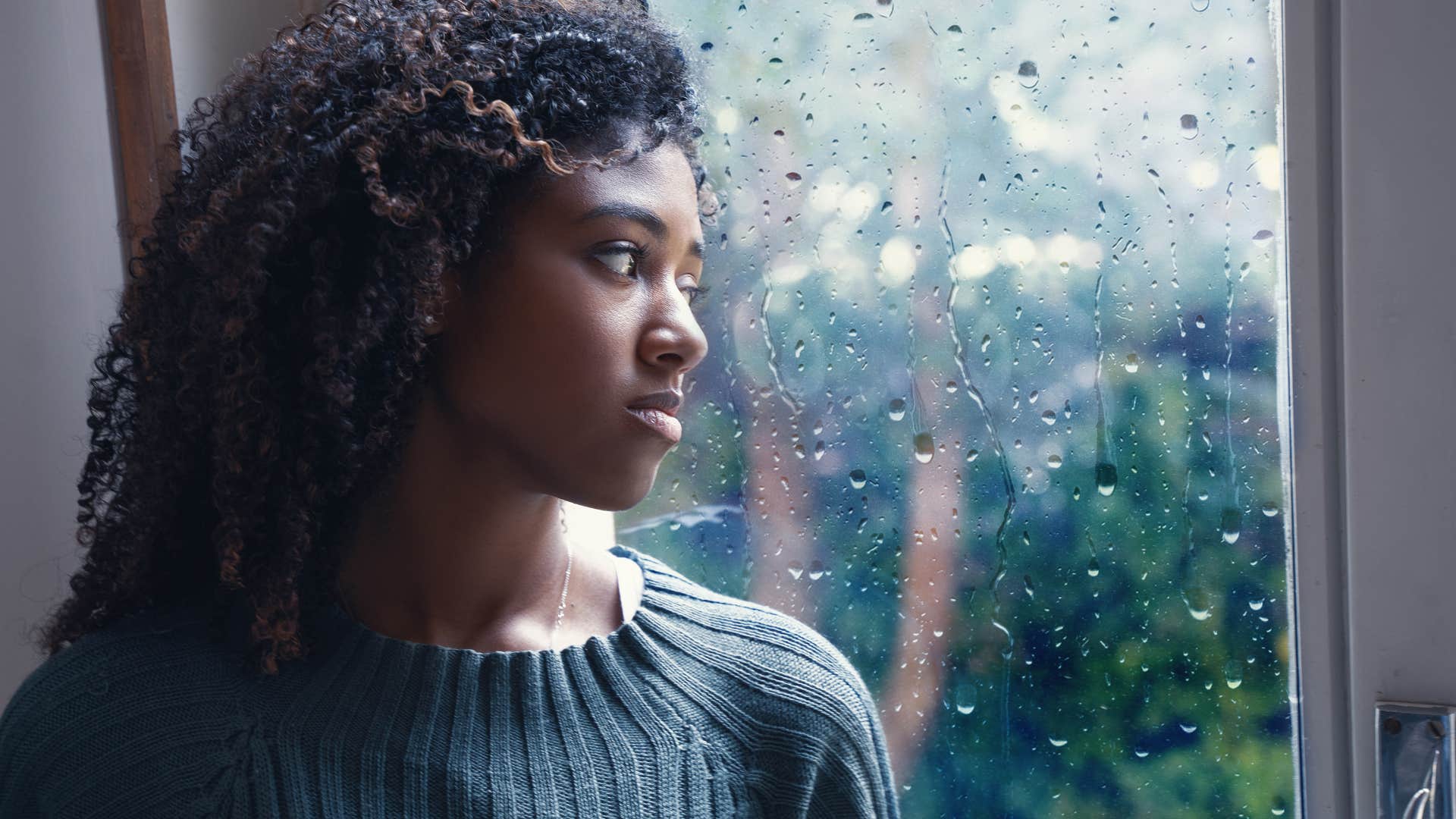 grieving woman looking sadly out a window