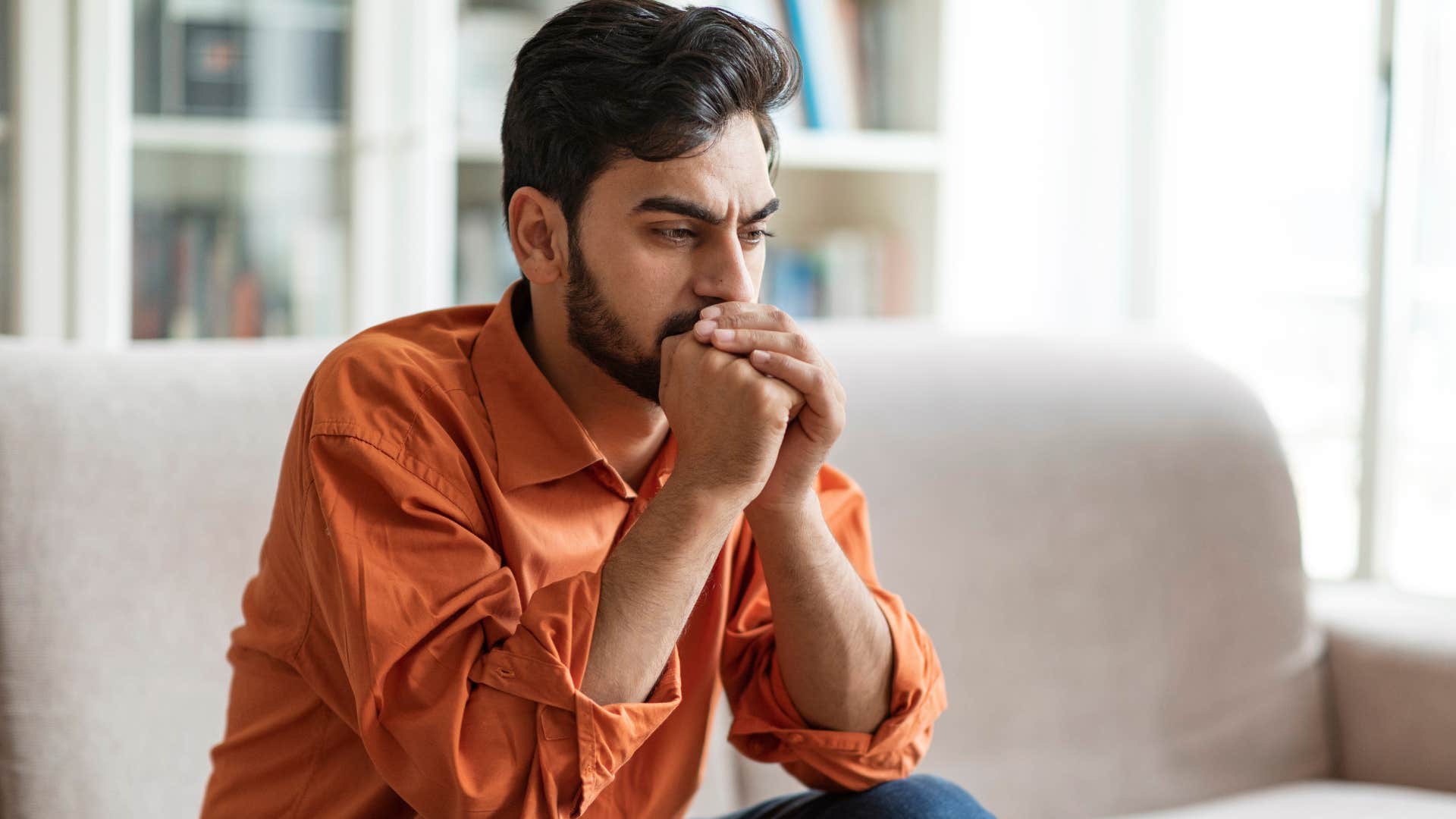 Insecure man sitting on his couch with his head in his hands