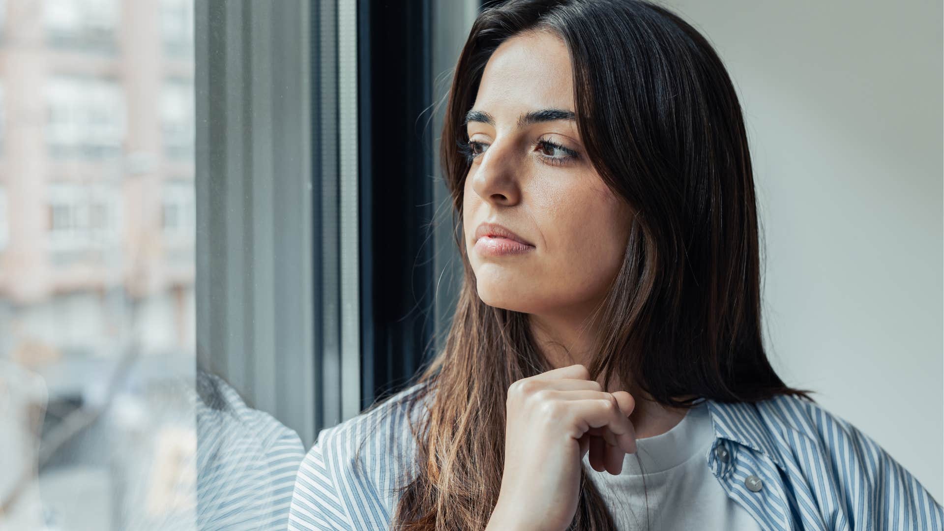 overly anxious woman looking out a window