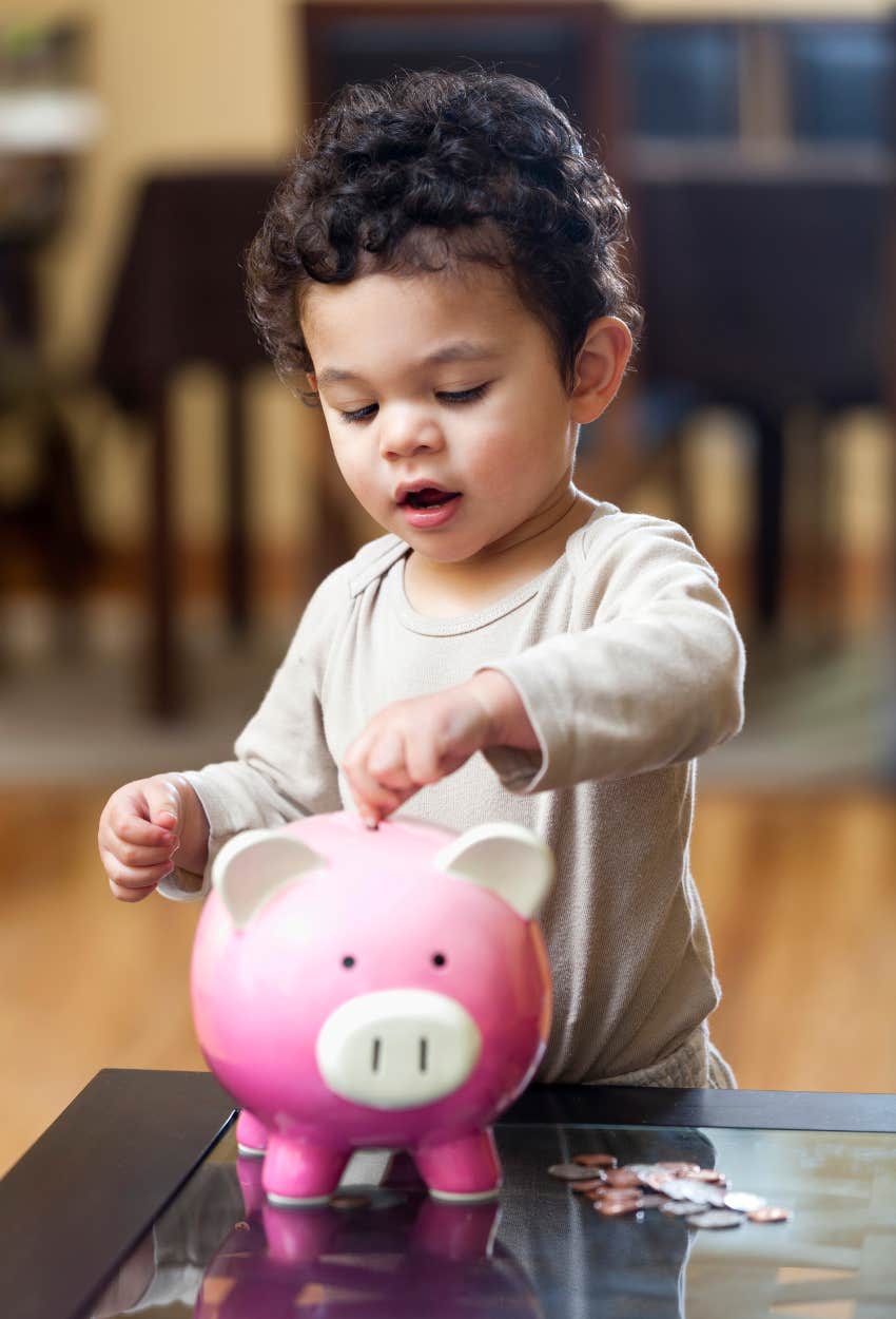 Little boy putting his allowance in piggy bank has a benefit of learning financial literacy