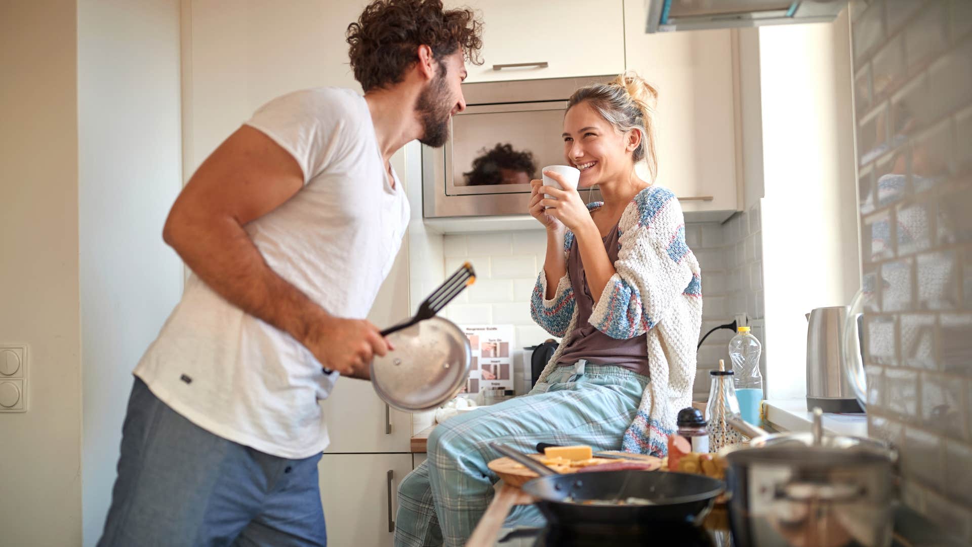 man multitasking making breakfast for his wife
