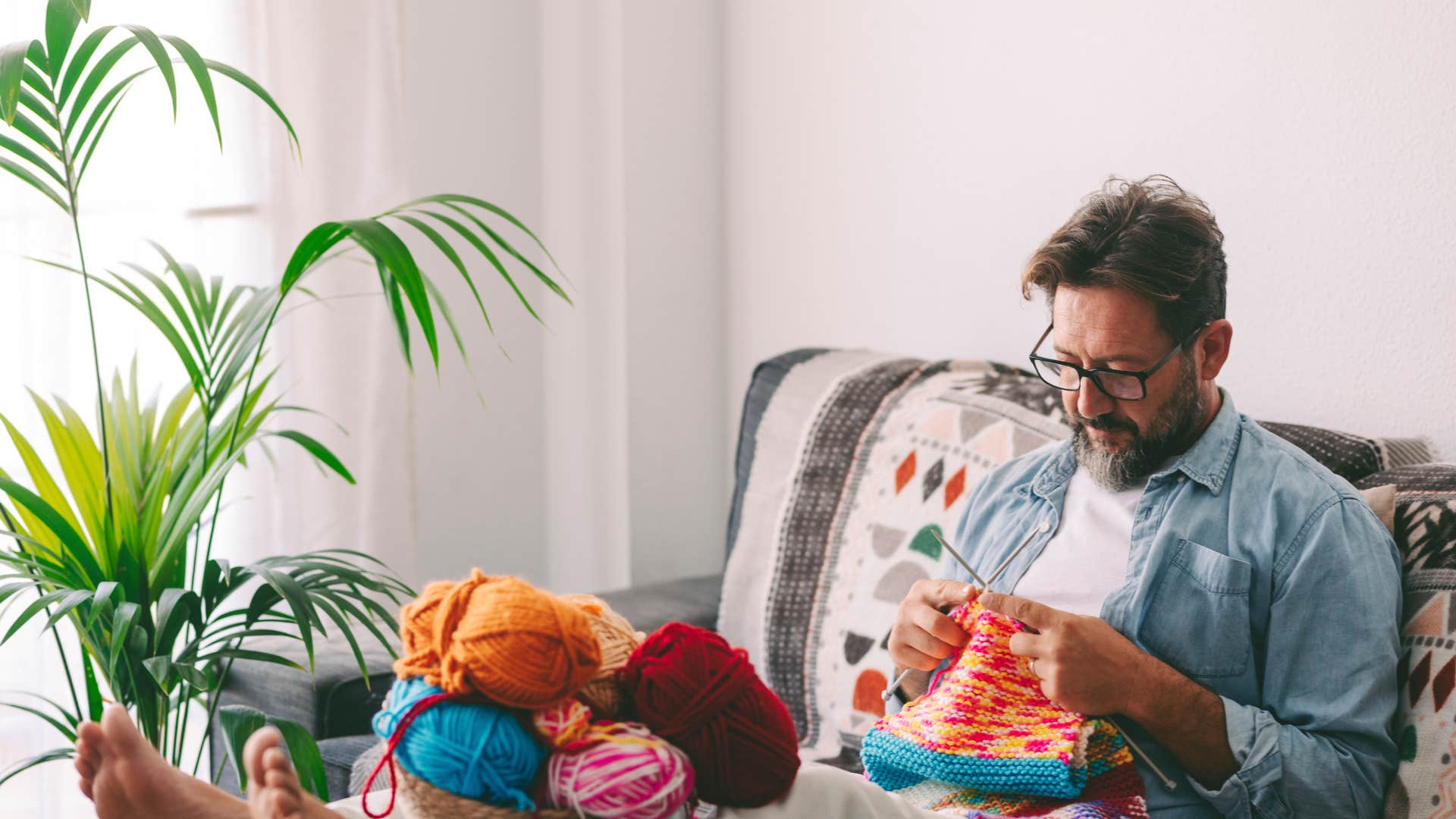 man sitting on couch and knitting