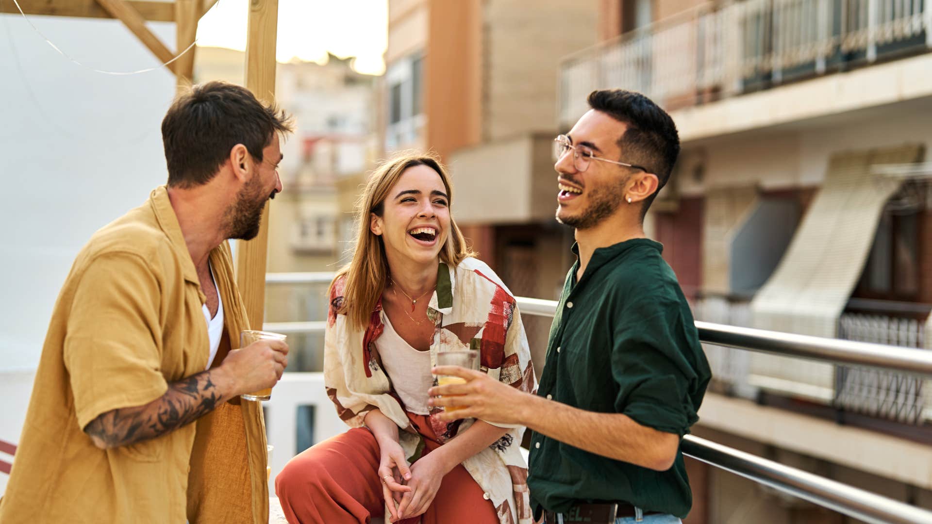 men laughing with woman outside treating her with kindness