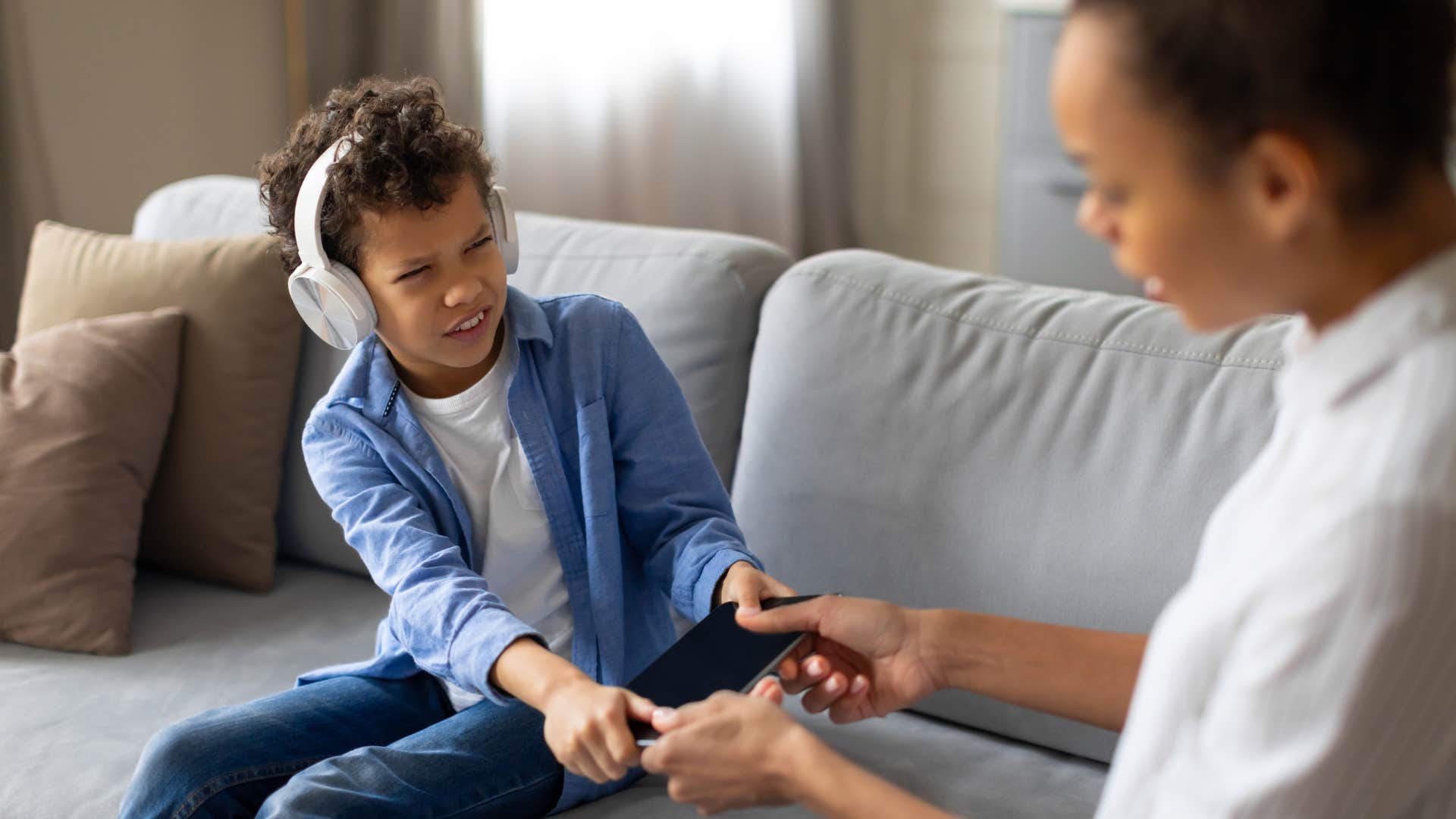 a young boy struggles with his mother over her taking his phone away