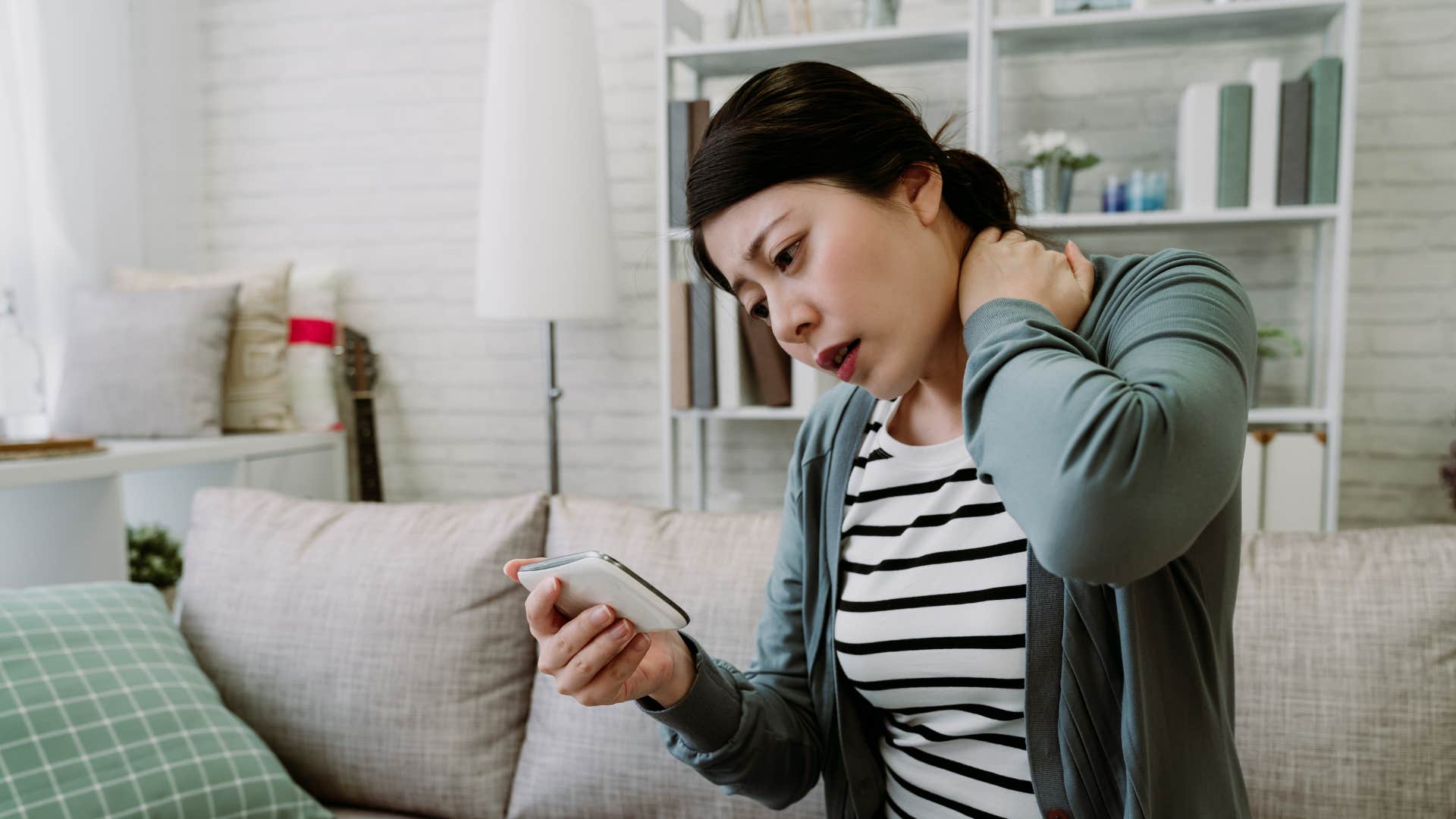 a woman rubs her back as it hurts from years of poor posture