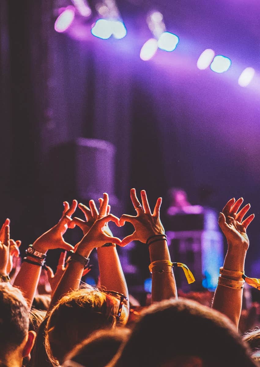 happy concert crowd holding hands up