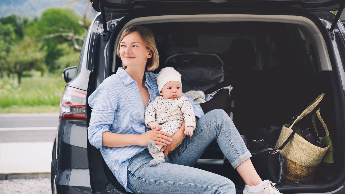 mom holding newborn while sitting in back of car