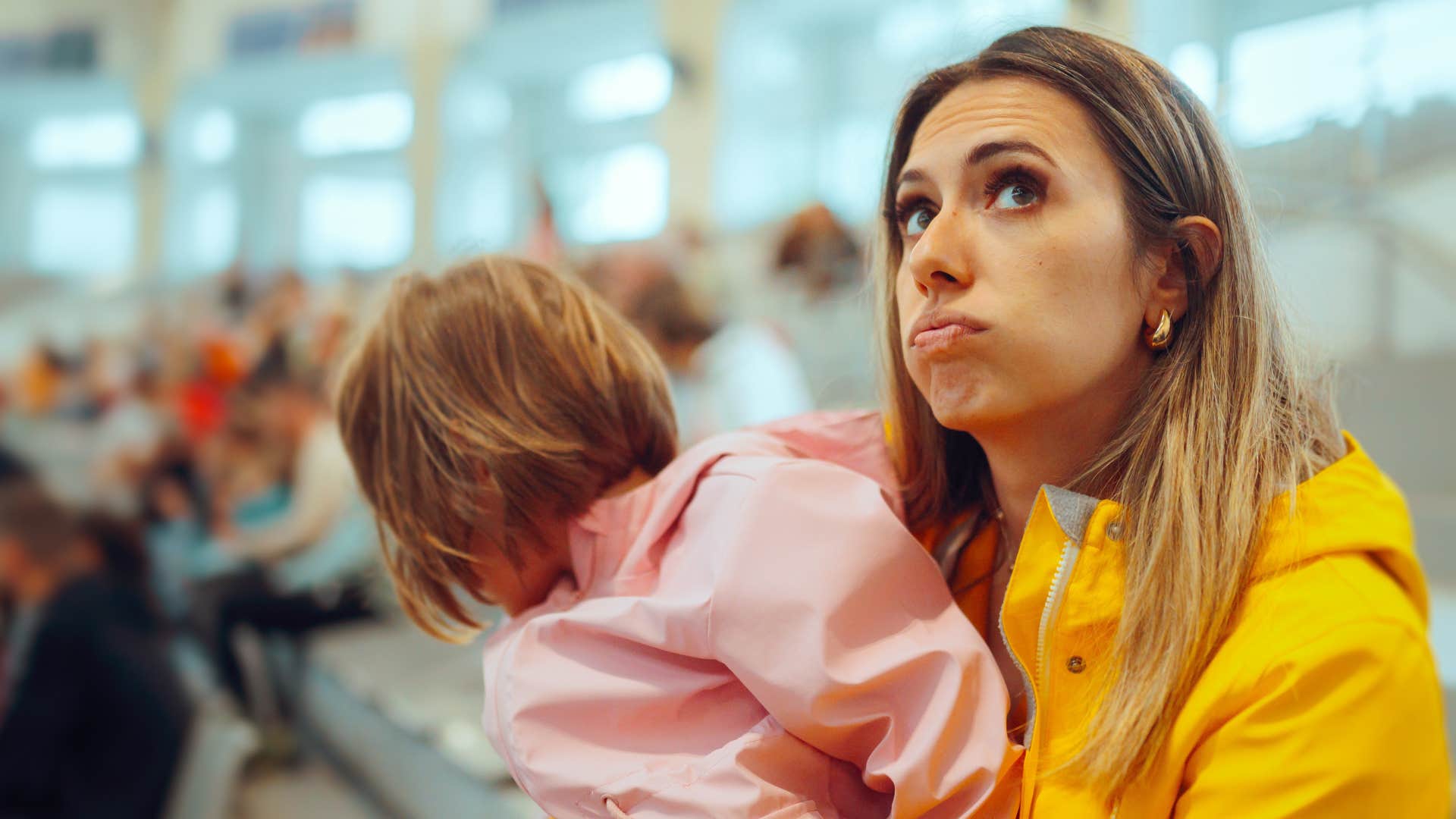 a woman holding her toddler tends to avoid crowds