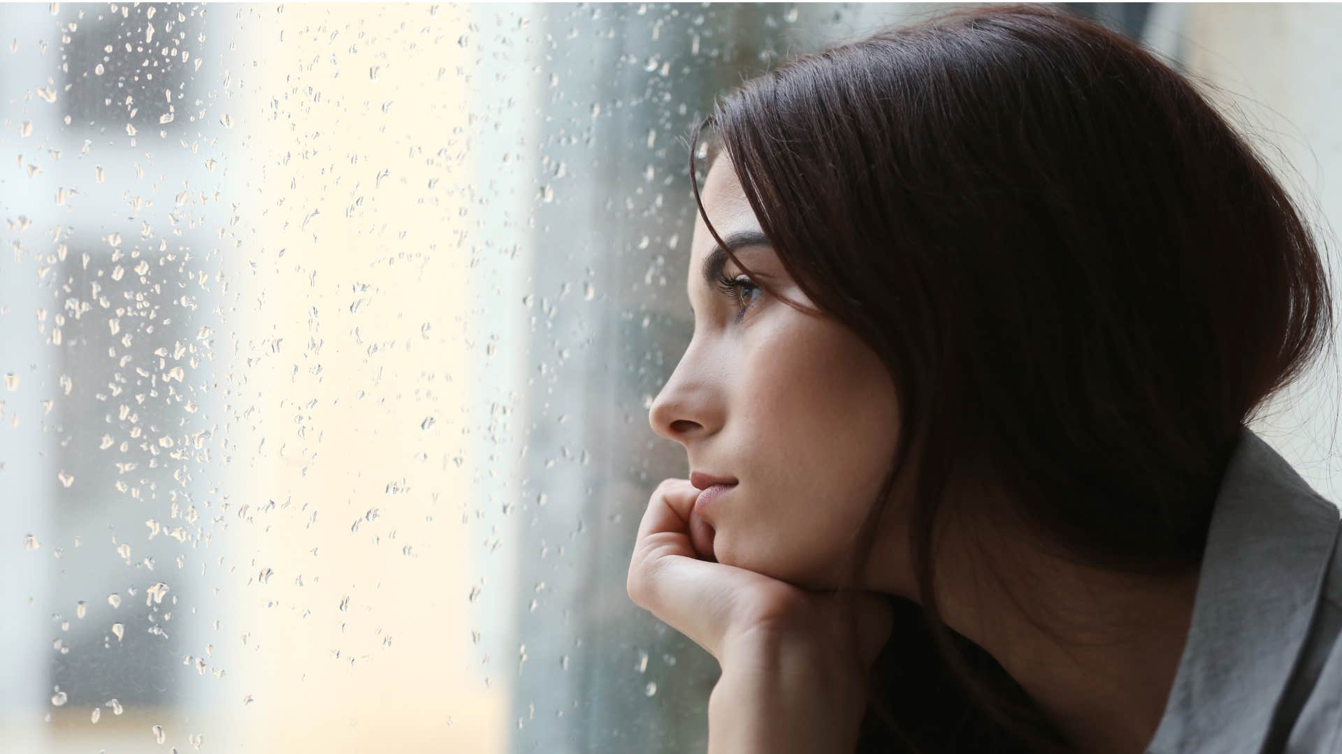 woman struggling to let go of the past as she stares out the window