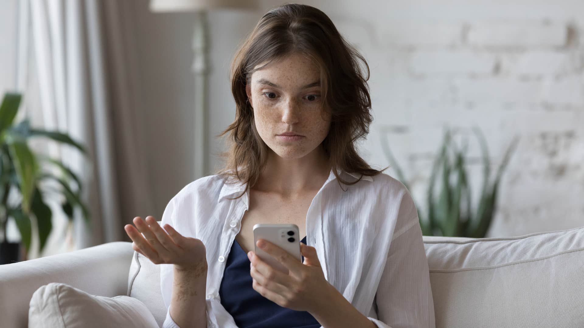 woman looking annoyed at phone as friend has a habit of sending too many videos