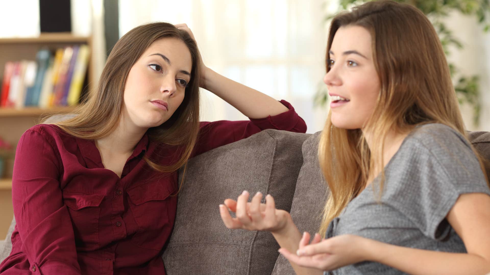 woman who never knows when to stop talking is talking while friend in red shirt looks at her annoyed