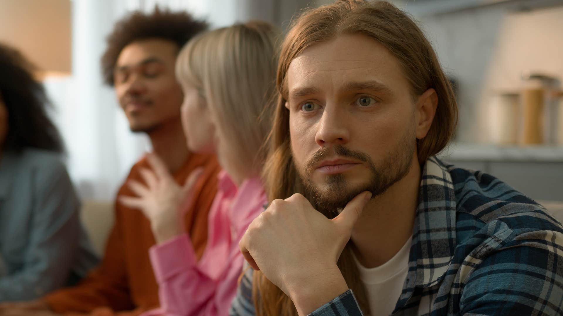 Introverted man looking away from his friends