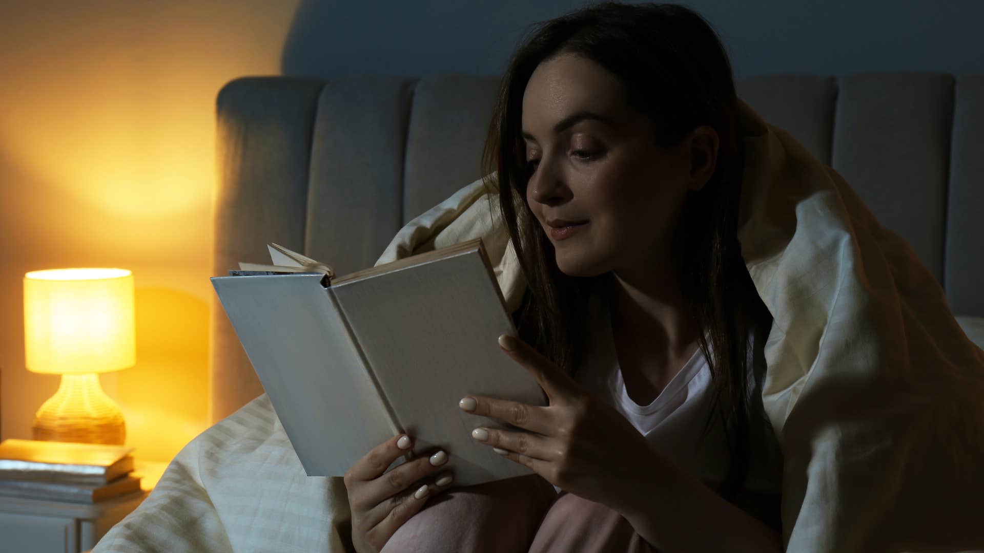 woman reading a book in bed before going to sleep