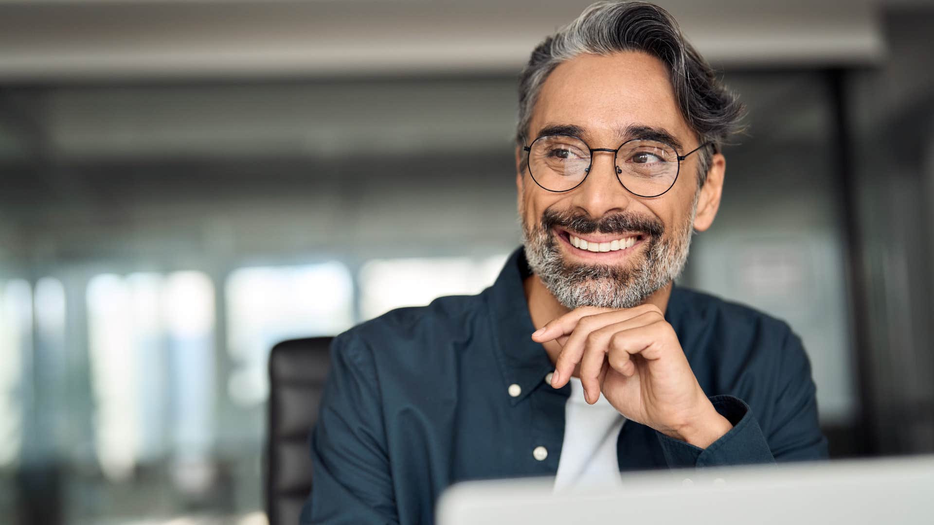 Man who's too busy for a phone call smiling at work.