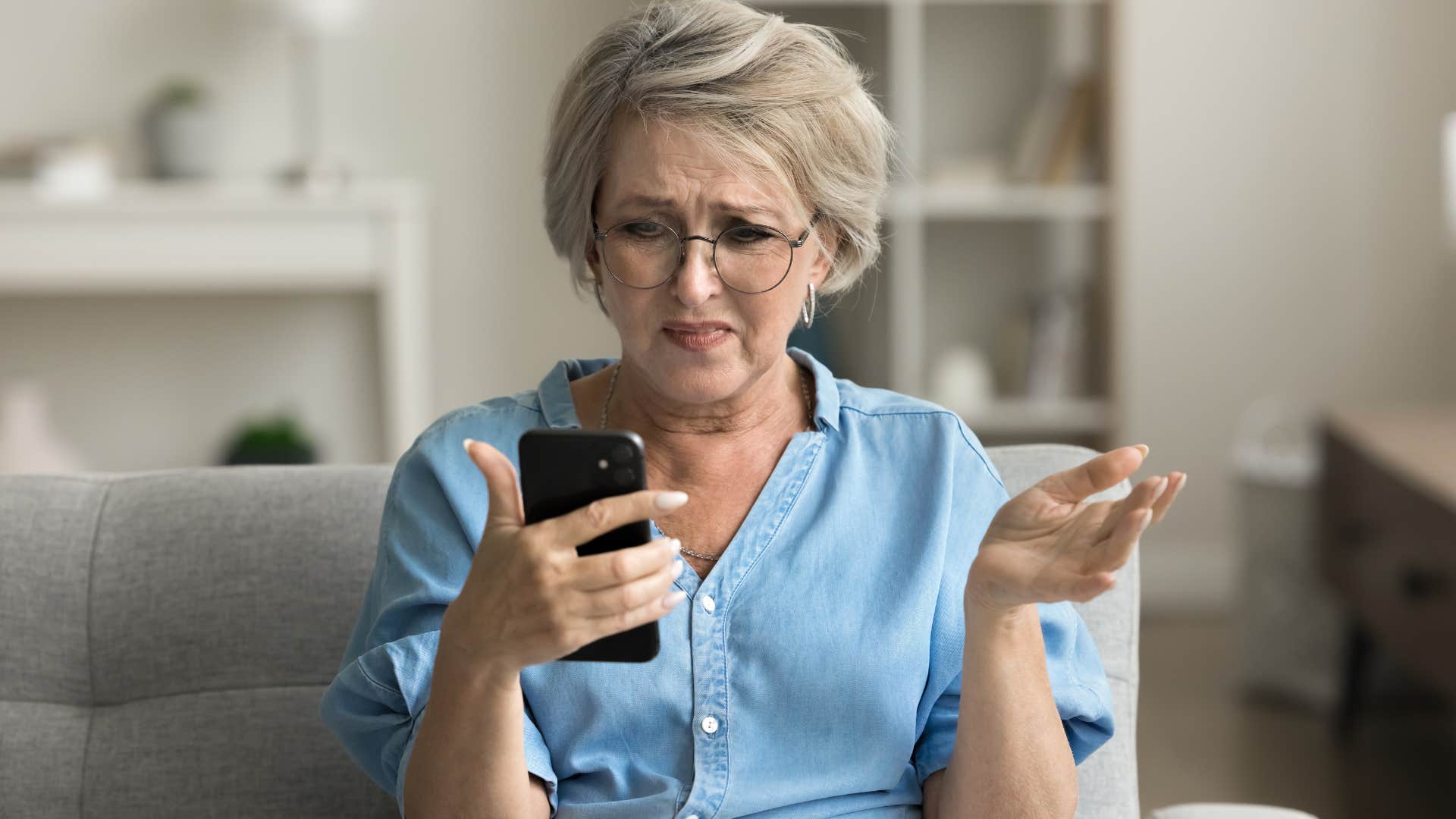 Woman with physical impairments looking annoyed at her phone.