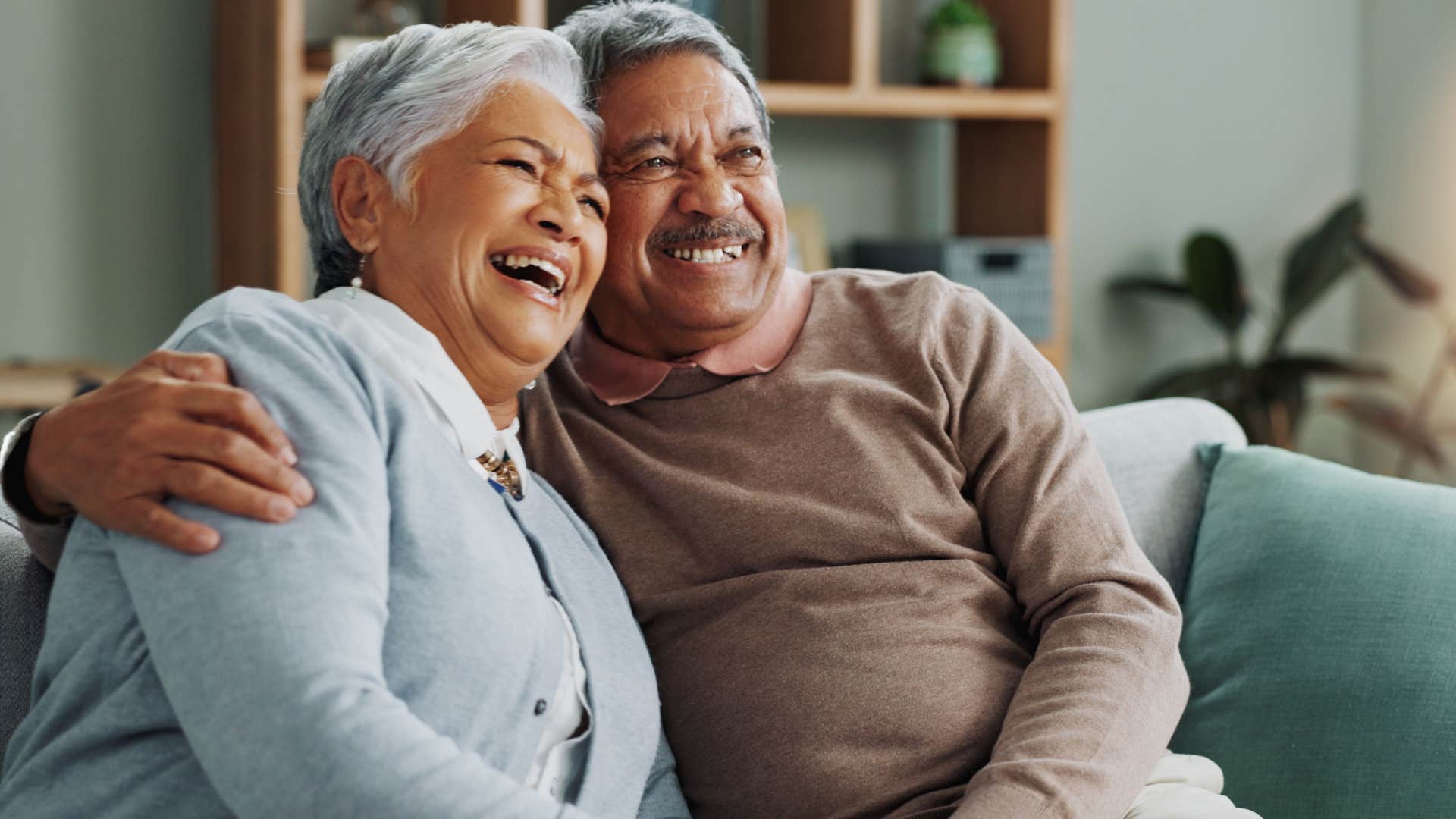 Emotionally secure couple smiling and hugging at home.
