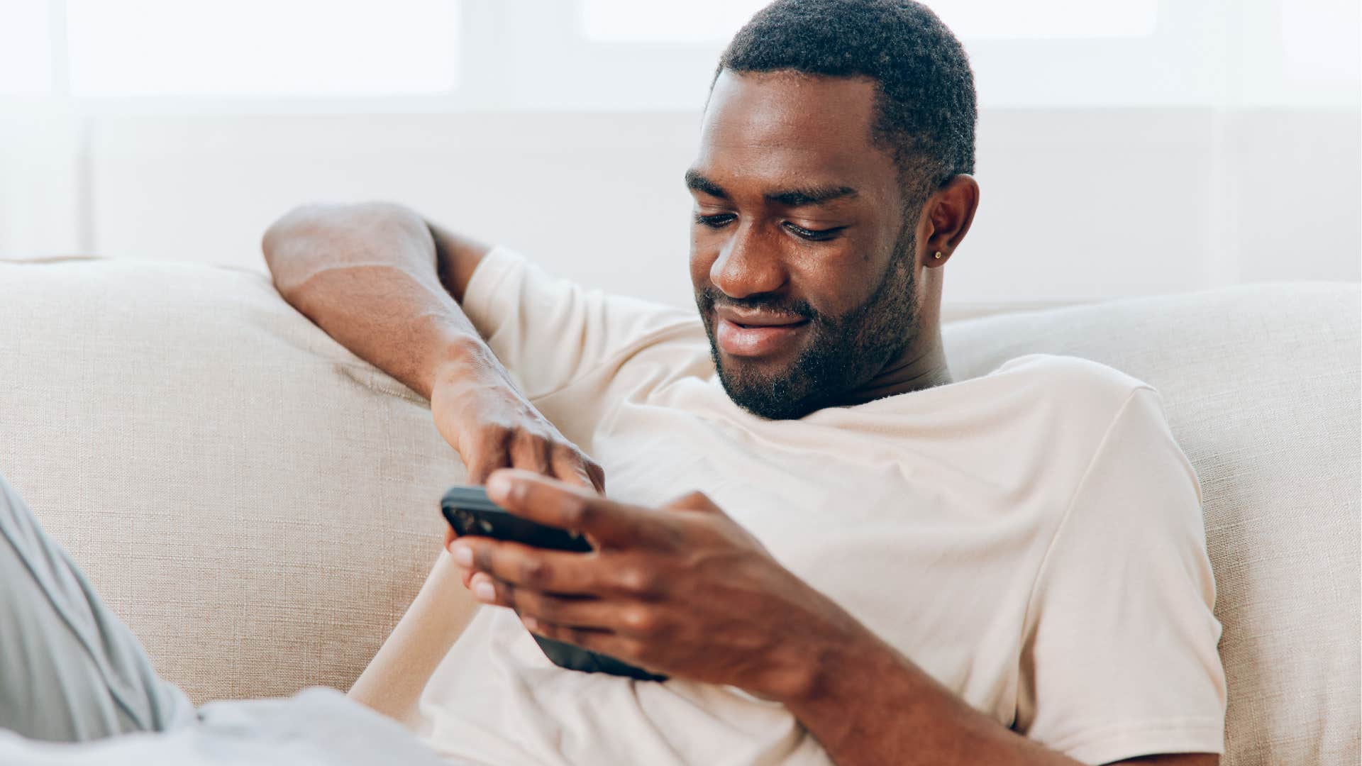 Self-assured man smiling and looking at his phone.