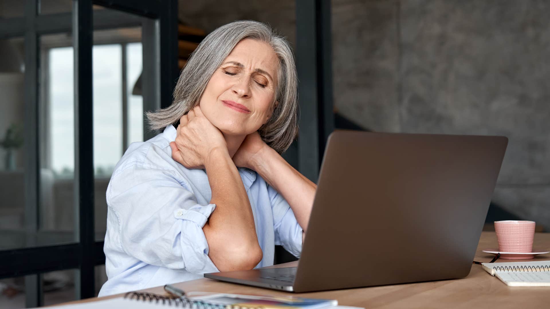 Woman who's limited by physical ailments holding her neck at work.