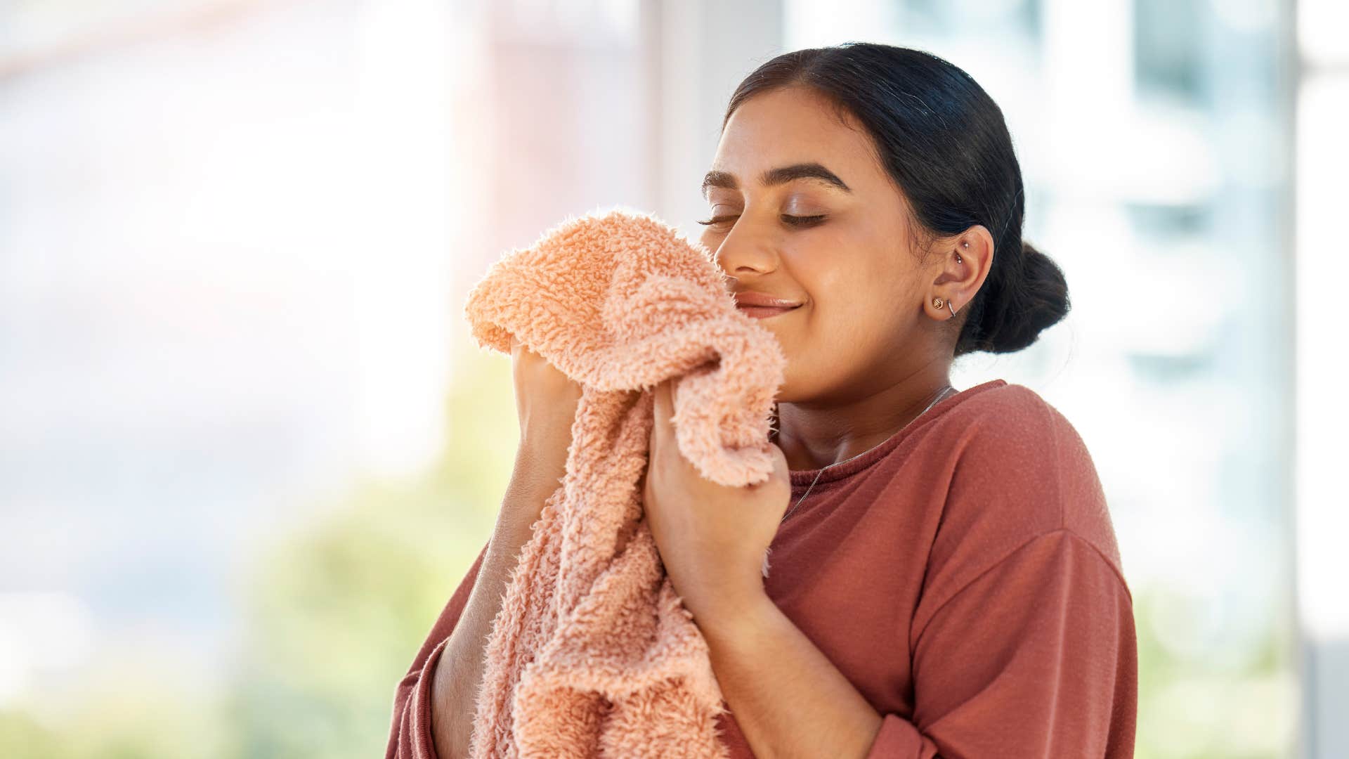 a woman smells her fresh towels that she plans on putting up for company