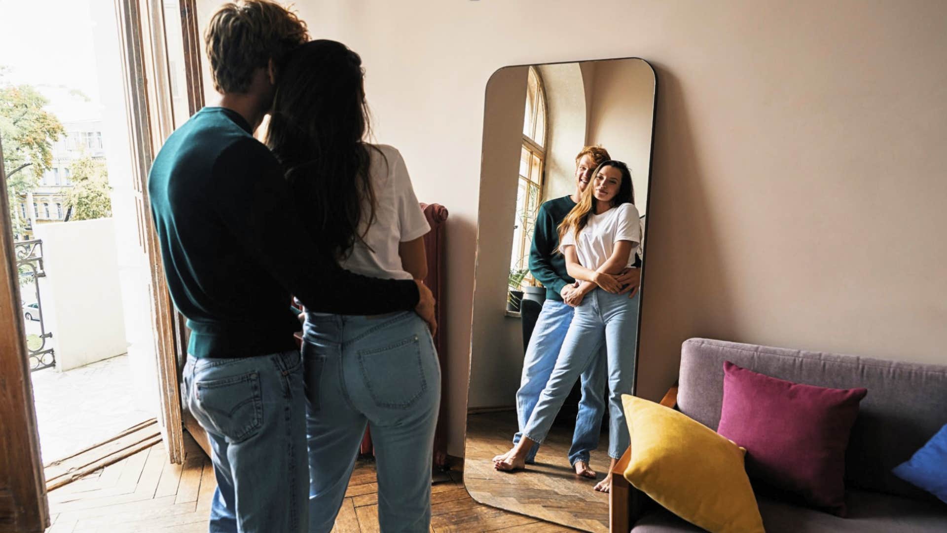 couple looks lovingly into the mirror in their home