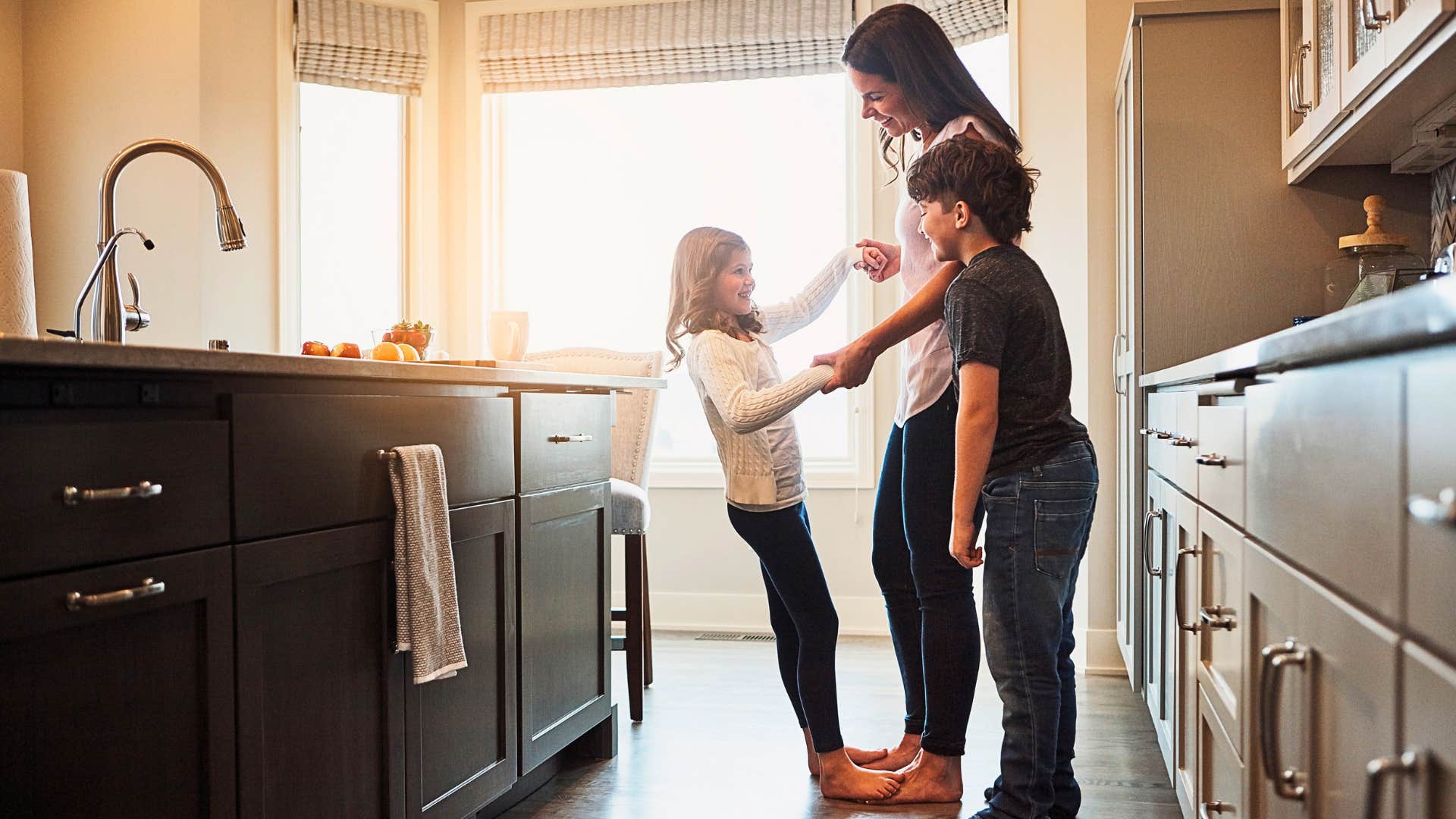 mother plays with her children in kitchen with uncluttered counters