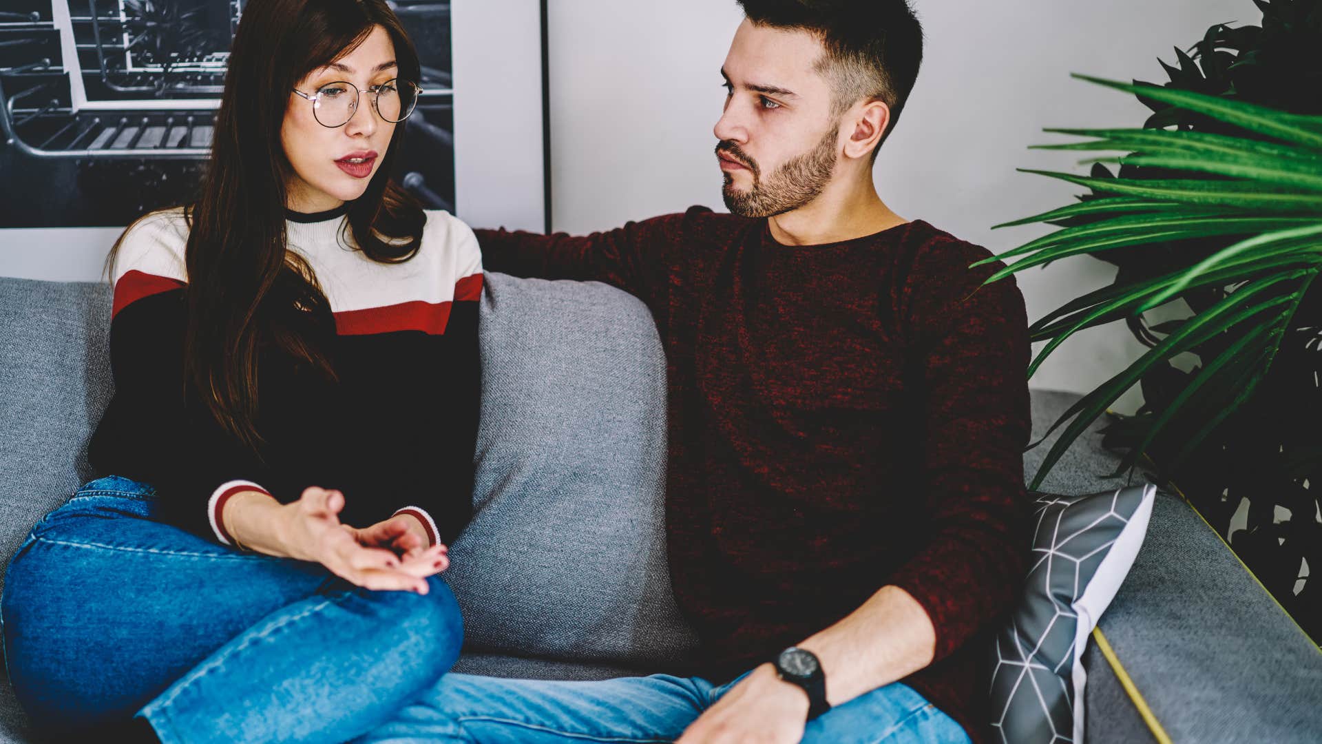 couple talking on the couch looking annoyed
