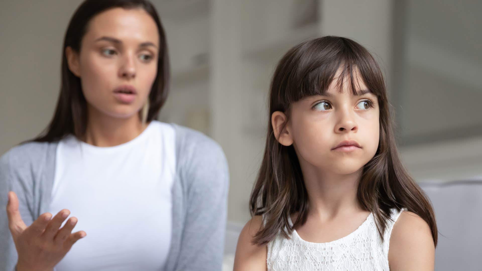 woman talking seriously to young daughter looking away