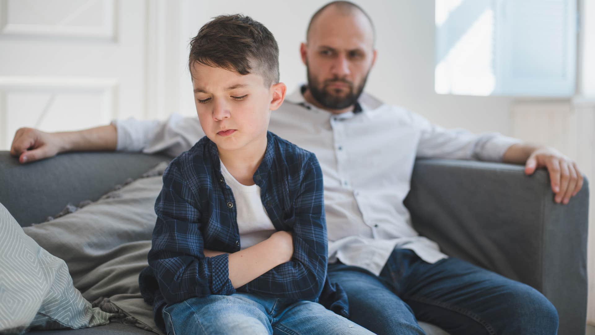 man scolding young son on couch