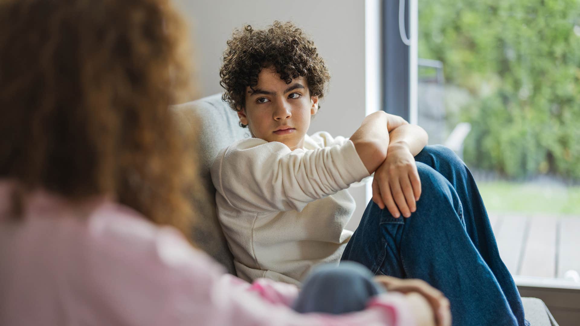 son in cream colored shirt glaring at mom as mom in pink shirt says don't talk back to me