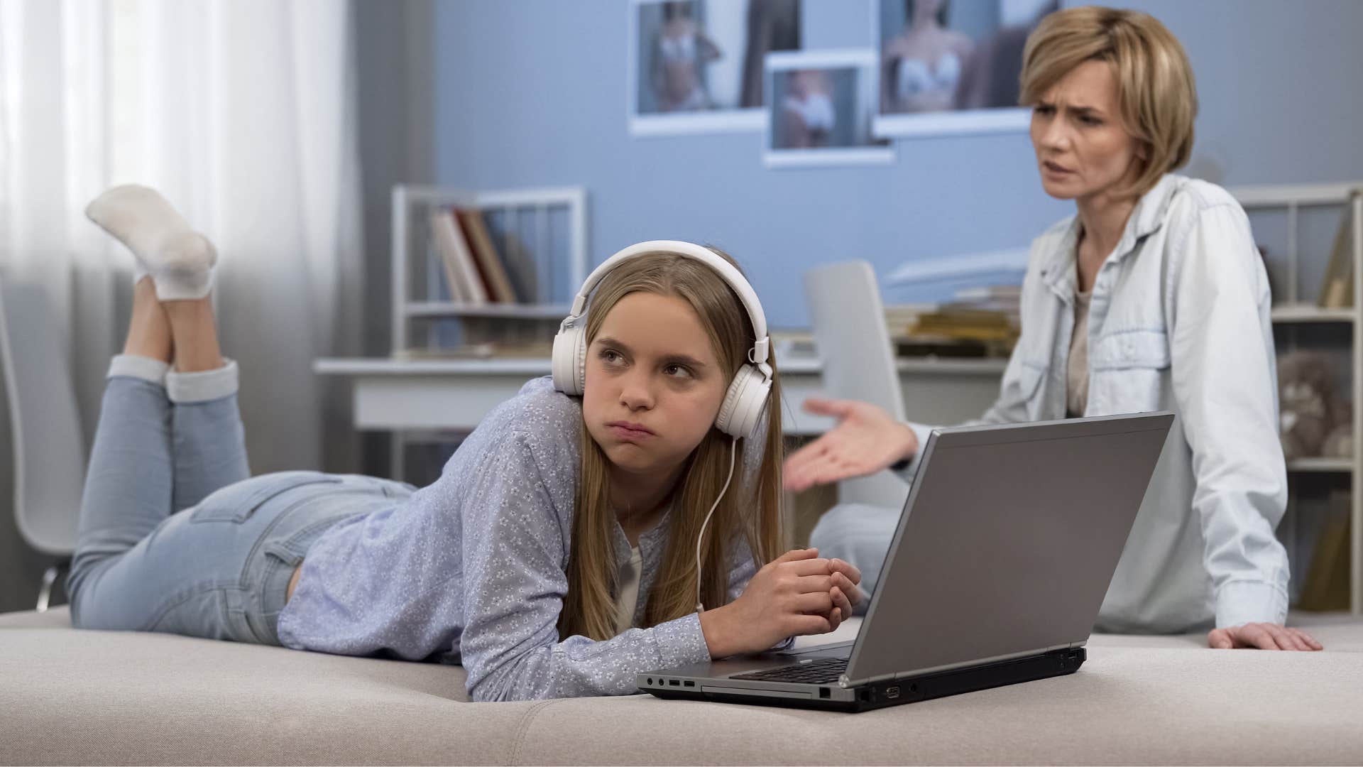 mom in white shirt telling daughter with headphones she should be grateful because she has a roof over her head and clothes on her back while daughter looks away in annoyance