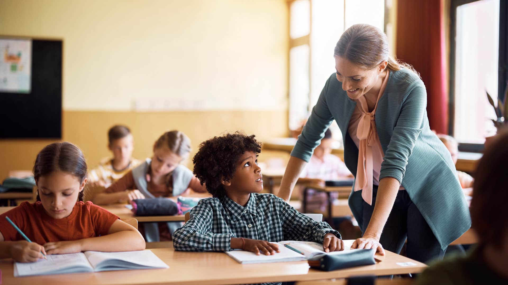 teacher talking to child who can't sit next to another student