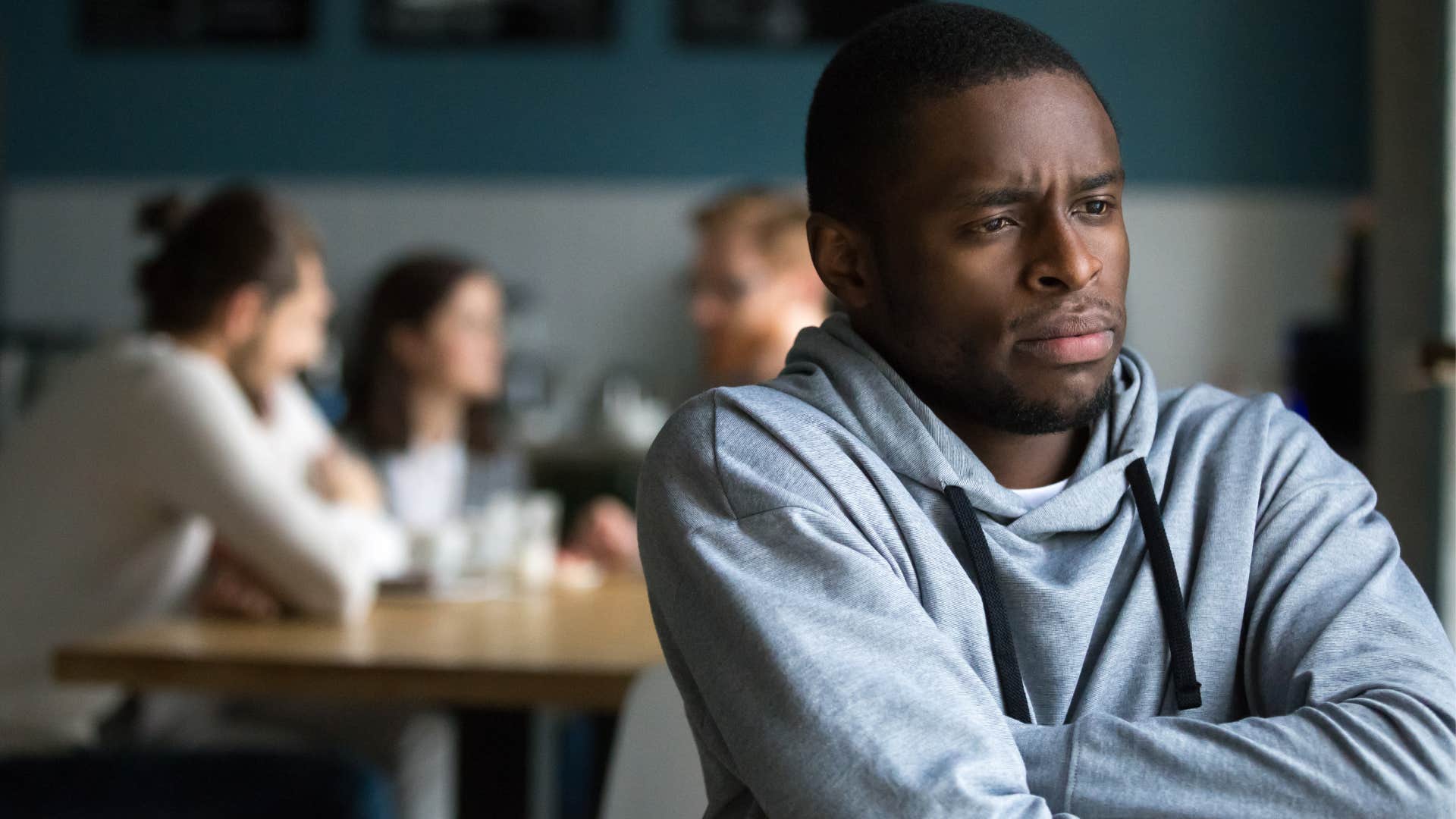 man thinking thanks for the invite turned away from his friends