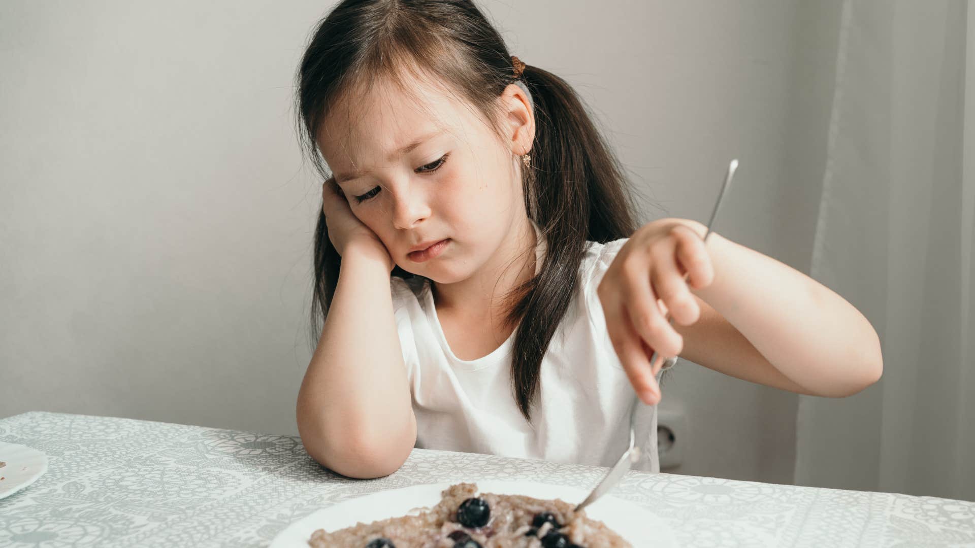 picky little girl eating food instead of going to bed hungry
