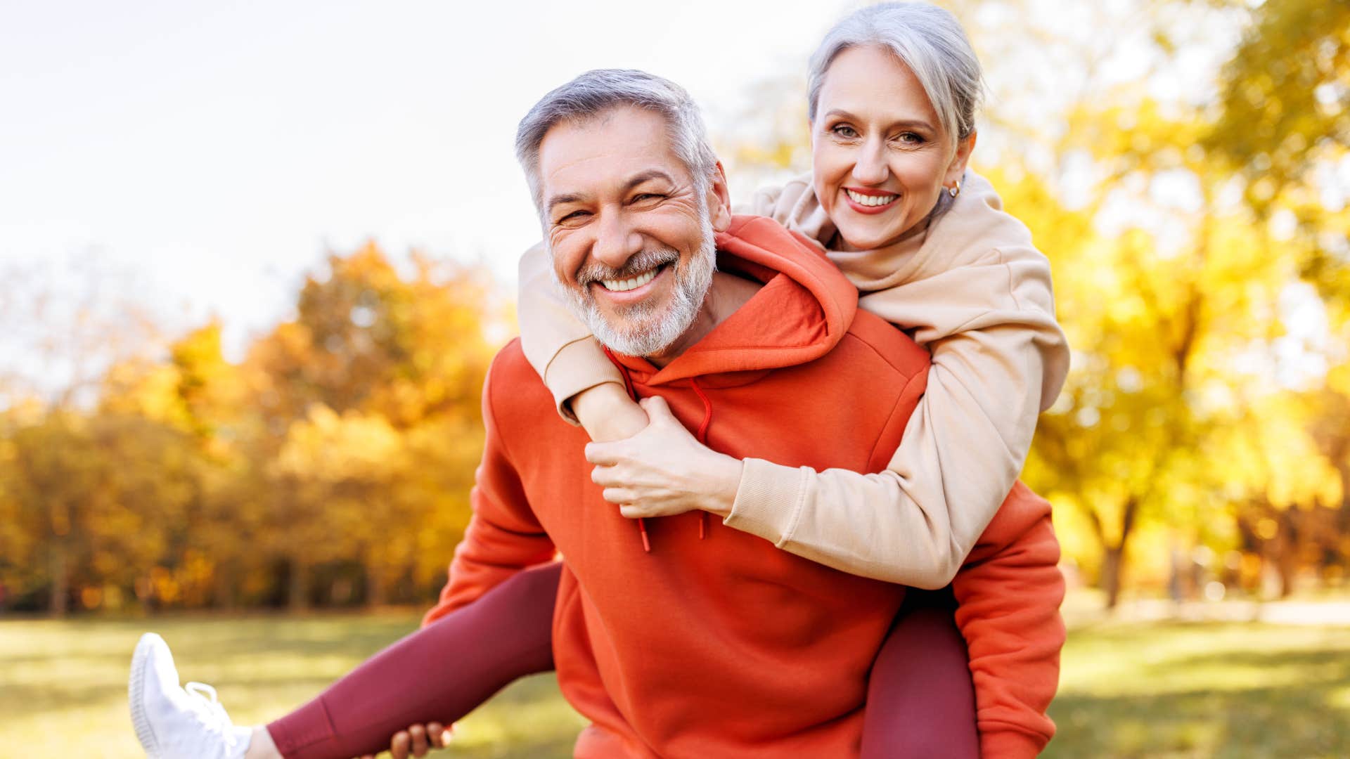 Hypervigilant man smiling and holding his wife on his back.