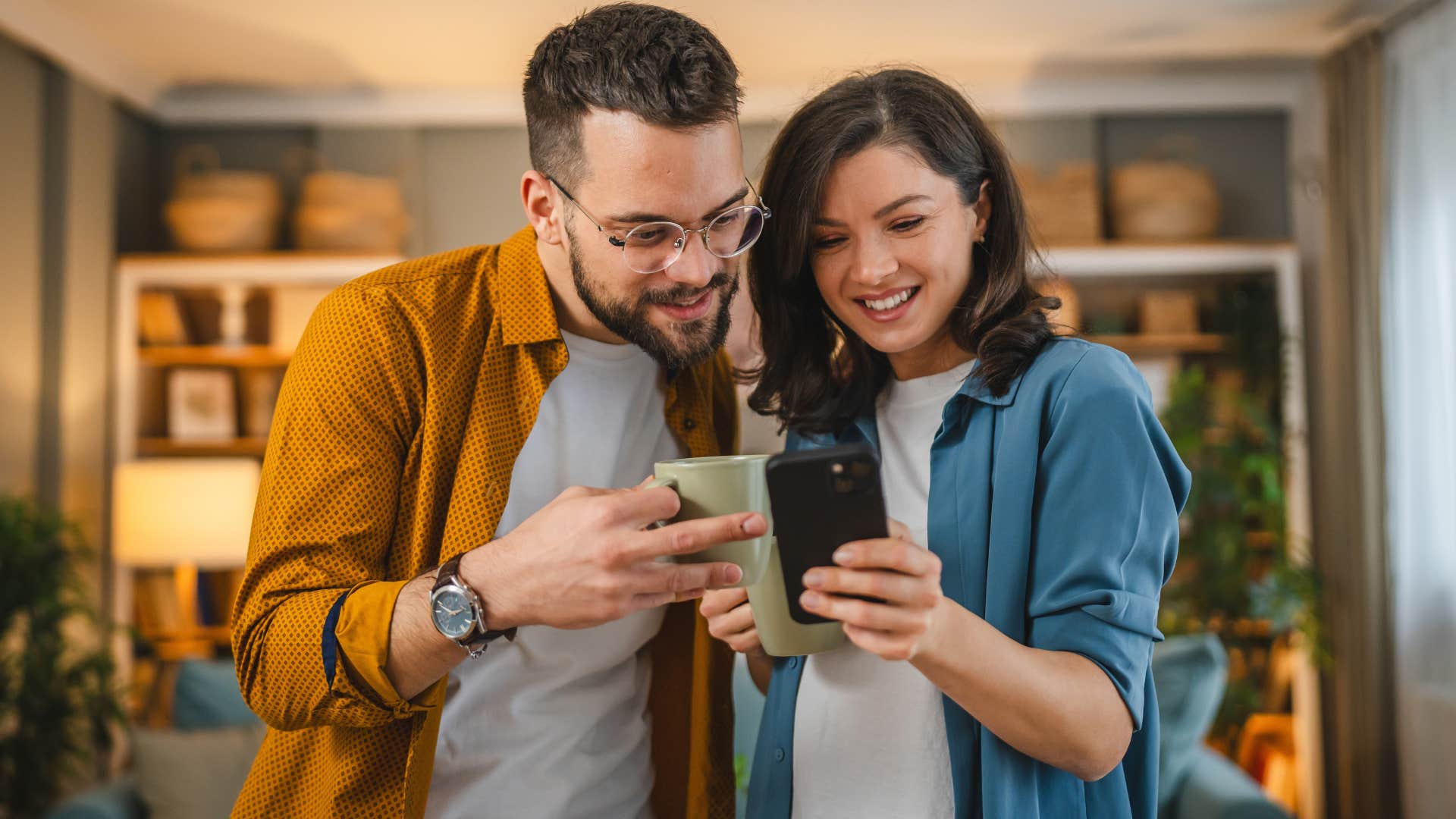 Man who remembers the little things smiling with his wife and looking at a phone.