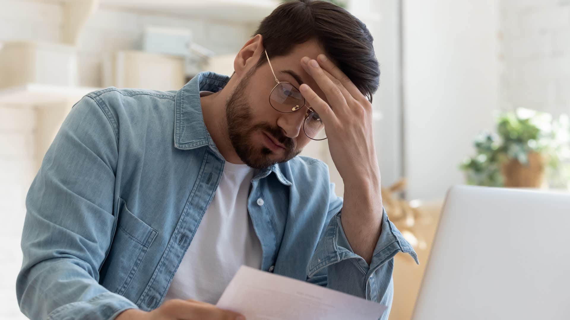 Upset man battling economic instability doing bills at home