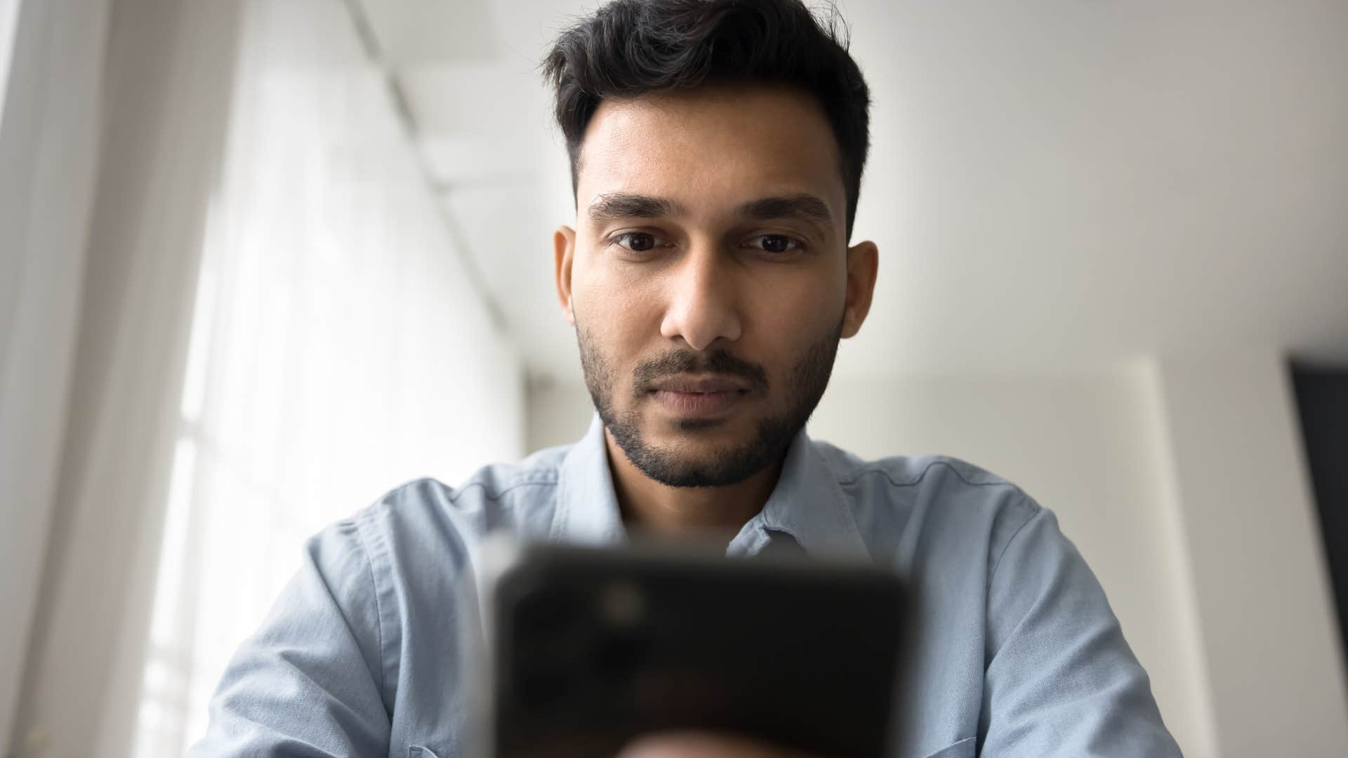Man with too much screen-time looking at his phone